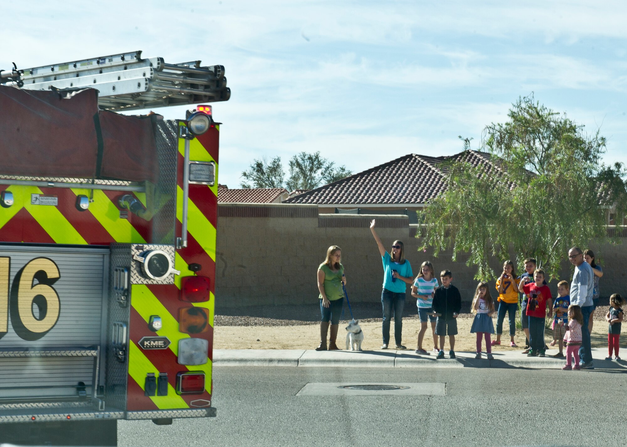 Holloman team members and dependents wave to firefighters during the Fire Prevention Week parade at Holloman Air force Base, N.M. Oct. 11. As a closing ceremony to Fire Prevention Week, the Emergency Services drive through Soaring Heights housing communities while sounding off their sirens and alarms. Emergency Services provided guided tours of the fire stations, fire response demonstrations, and held a fire fighter challenge as part of their contribution to fire safety awareness and to those that served before them. (U.S. Air Force photo by Staff Sgt. E’Lysia Wray/Released)