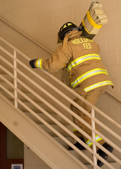 A Holloman Fire Emergency Services firefighter rushes up stairs with a hotel pack at the 2nd Annual Fire Fighter Challenge at Holloman Air Force Base, N.M. Oct. 10. Firefighters also participated in other challenge events including a 45-pound hose roll pull, the force sled also known as the Kiser sled, a serpentine run, a 100-foot hose pull, and a 100-foot dummy drag. The purpose of the fire fighter challenge is to let the general public have a chance to try the everyday tasks that firefighters have to encounter. (U.S. Air Force photo by Staff Sgt. E’Lysia Wray/Released)