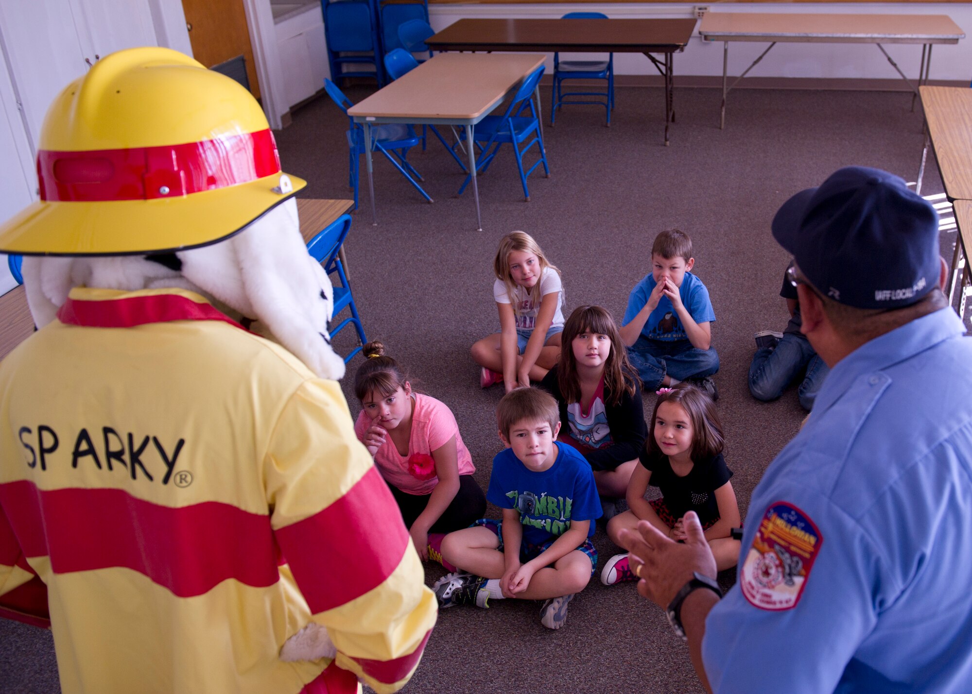 Sparky the Fire Dog and Tony Padilla, Holloman Fire Emergency Services fire inspector, visit children Oct. 7 at the Holloman Elementary School. They talked about the importance of checking smoke detector batteries on a monthly basis. They also explained the procedures on how to call for help in case of an emergency and how to safely get out of a fire. (U.S. Air Force photo by Staff Sgt. E’Lysia Wray/Released)