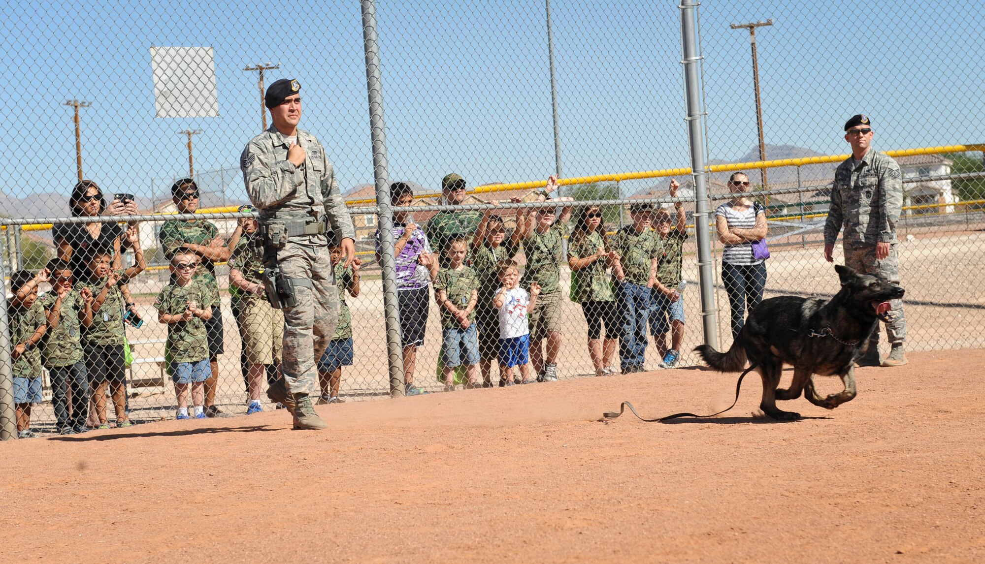 Children participating in the Nellis and Creech Kids Deployment watch Staff Sgt. Brandon Steede, 99th Security Forces Squadron military working dog handler, and MWD Pjak put on a demonstration at Nellis Air Force Base, Nev., Oct. 11, 2014. Children were shown the discipline of the MWD as he demonstrated listening to commands, guarding a suspect and a few take downs. (U.S. Air Force photo by Staff Sgt. Victoria Sneed)