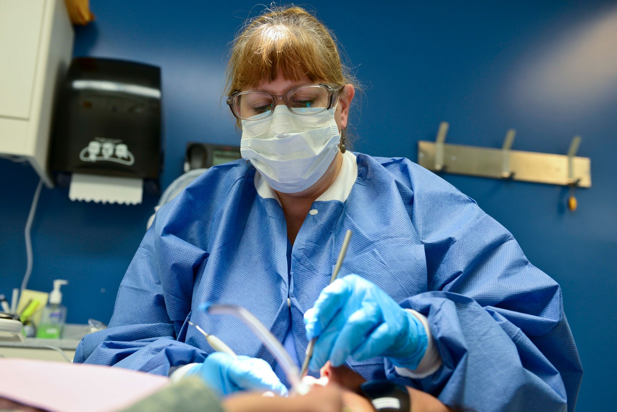 Cindy Delapena, Dental Command registered dental hygienist, performs a cleaning on a patient at Fort Eustis, Va., Oct. 15, 2014. During a cleaning, patients have plaque removed from their teeth, their teeth polished and are given a fluoride treatment. (U.S. Air Force photo by Airman 1st Class Kimberly Nagle/Released)    