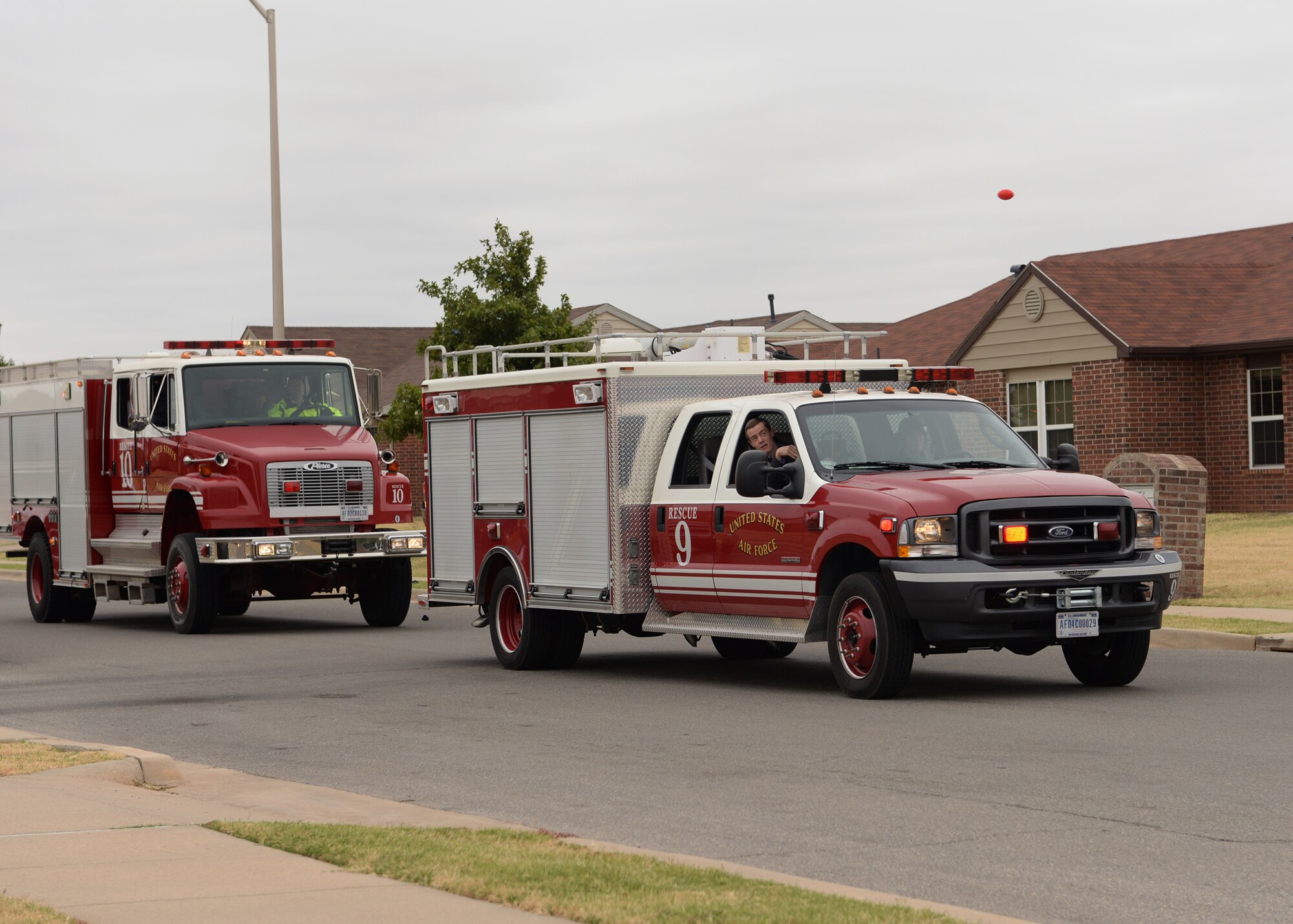 ALTUS AIR FORCE BASE, Okla. – Firefighters from the 97th Civil Engineer Squadron drive through base housing during the Fire Prevention Week parade Oct. 11, 2014. The parade was part of several events held throughout the week to raise awareness for fire safety. (U.S. Air Force photo by Airman 1st Class Nathan Clark/Released)