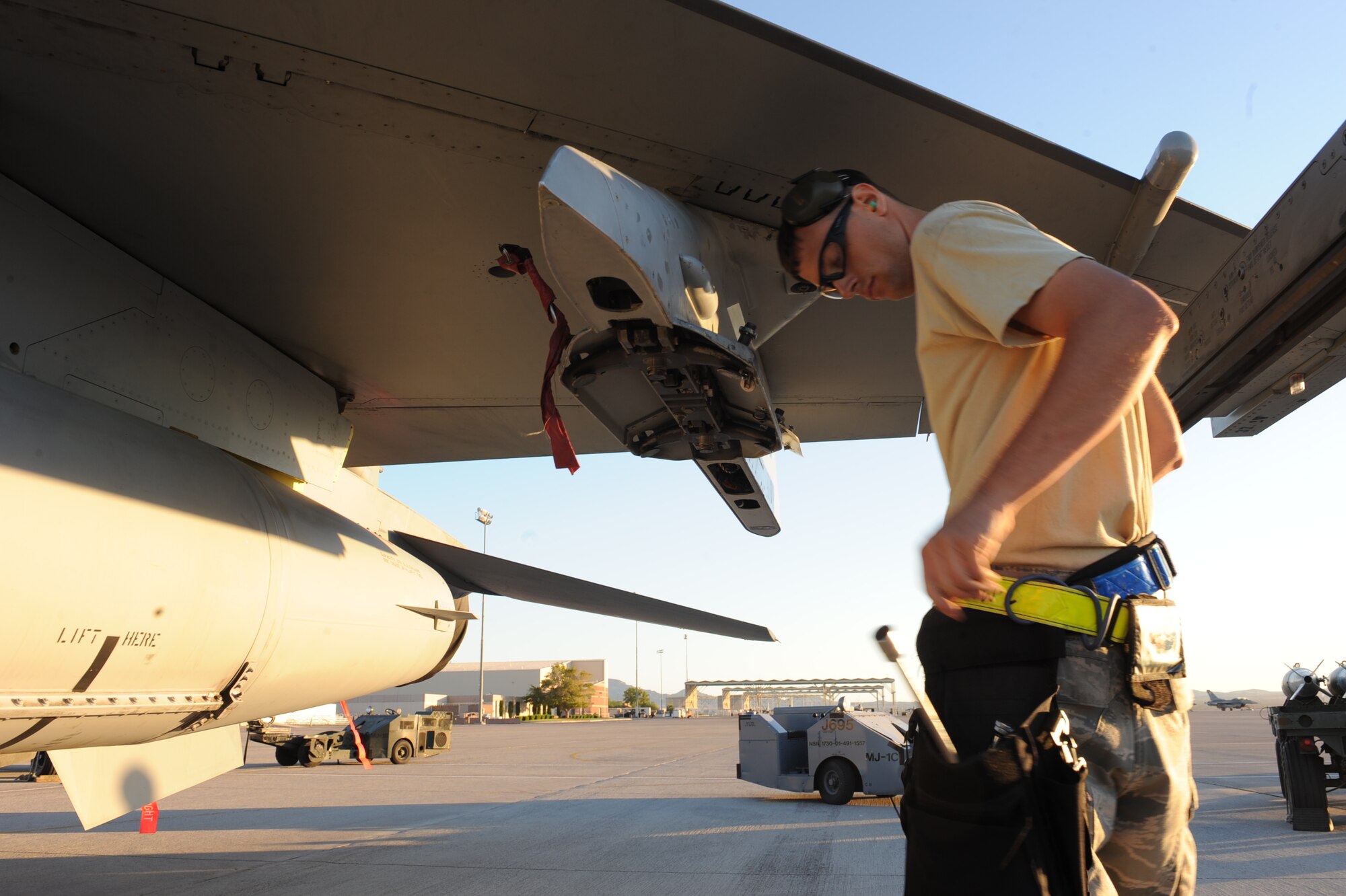 Senior Airman Tavish Macomb, 57th Aircraft Maintenance Squadron Viper Aircraft Maintenance Unit aircraft armament systems journeyman, reaches for a tool in preparation to load a missile on an F-16 Fighting Falcon during a quarterly weapons load crew competition at Nellis Air Force Base, Nev., Oct. 10, 2014. The load crew competition tests Airmen on their positional proficiency, safety, and the ability to follow technical orders. (U.S. Air Force photo by Staff Sgt. Victoria Sneed)