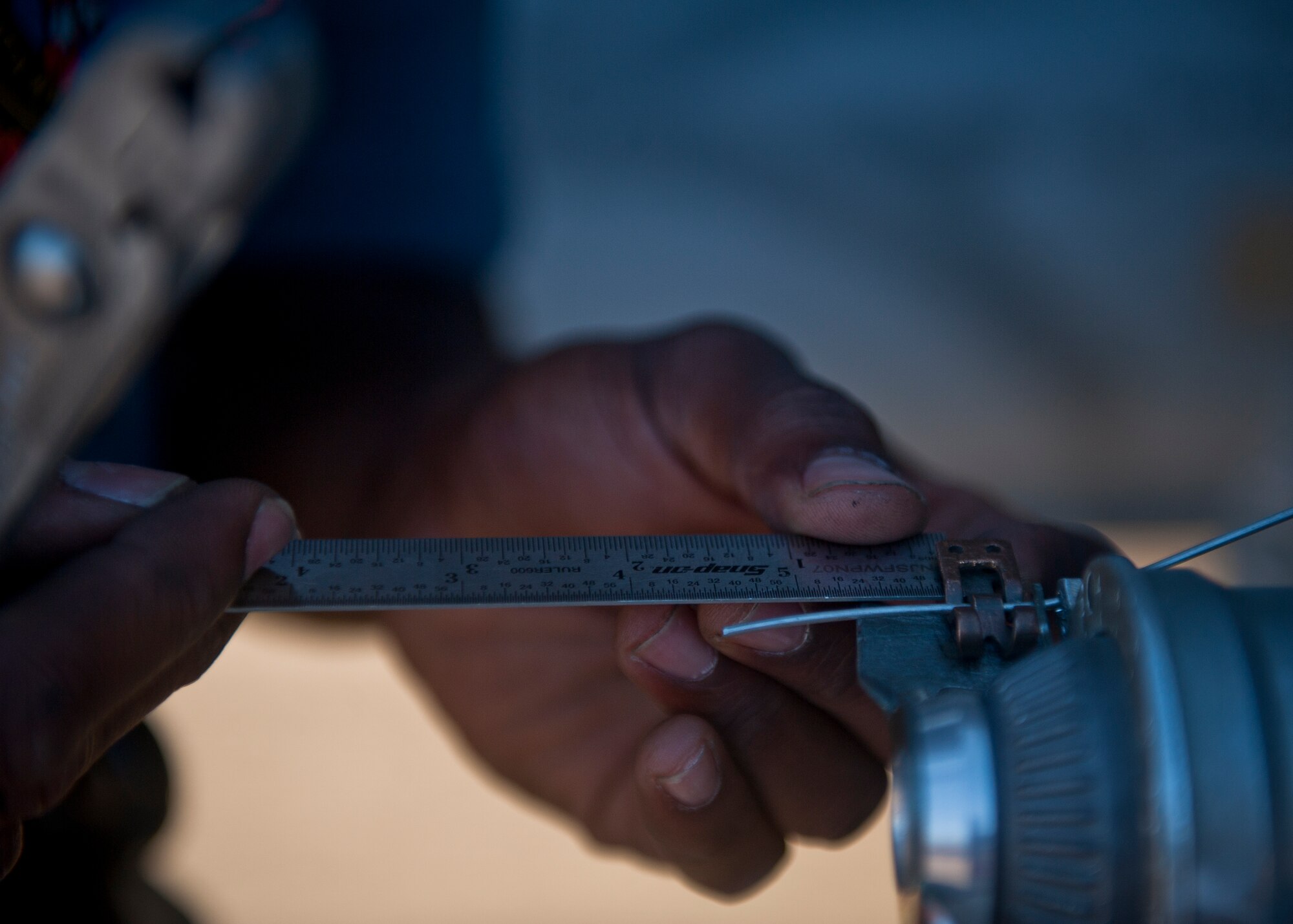 Airman 1st Class Keith Simpson, 57th Aircraft Maintenance Squadron Tomahawk Aircraft Maintenance Unit weapons loader, secures the connection between a munition and an aircraft during a quarterly weapons load crew competition at Nellis Air Force Base, Nev., Oct. 10, 2014. During a competition, each crew member has a set of tasks to carry out and work in teams of three or four to properly load weapons on an aircraft. (U.S. Air Force photo by Staff Sgt. Siuta B. Ika)