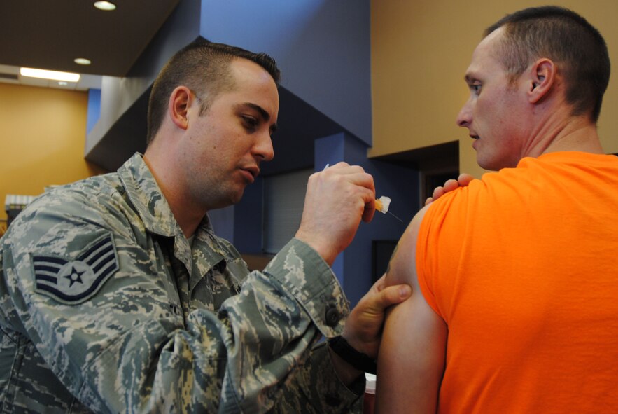 Staff Sgt. Michael Shea, 319th Medical Operation Squadron NCO in-charge of primary care, injects Staff Sgt. Jere Ross, 319th Air Base Wing chaplain assistant, with a flu vaccine Oct. 10, 2014, at the Community Activities Center on Grand Forks Air Force Base, N.D. The 28-year-old from Clear Lake, S.D., was named the Grand Forks AFB Warrior of the Week for the third week of October 2014. (U.S. Air Force photo/Staff Sgt. Luis Loza Gutierrez)
