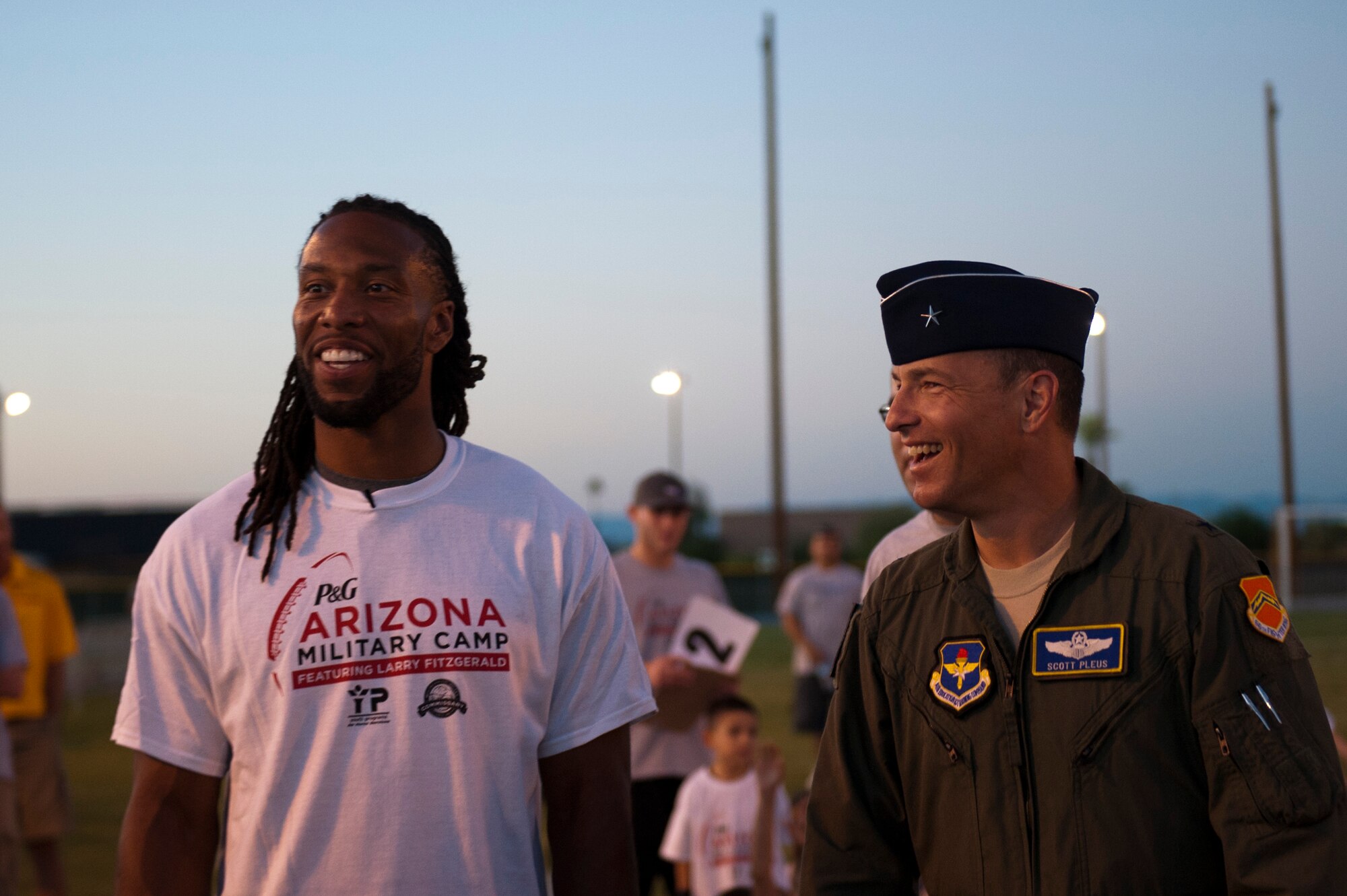 Brig. Gen. Scott Pleus, 56th Fighter Wing Commander, talks with Larry Fitzgerald, seven time pro-bowl wide receiver for the Arizona Cardinals, during a two-day football camp held for military children at Luke Air Force Base, Arizona, Oct. 13, 2014. The camp ran by ProCamps Worldwide, specialized in football fundamentals, with campers receiving instruction from Fitzgerald and football coaches from the local area. (U.S. Air Force photo/Staff Sgt. Staci Miller)