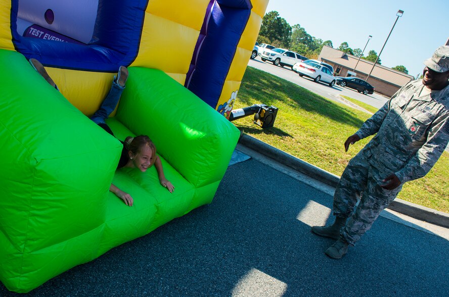 Miranda Crane, niece of Senior Master Sgt. Alfred Venditti, 23d Maintenance Group, laughs along with Tech. Sgt. Phillip Burns, 23d Civil Engineer Squadron fire inspector, after jumping through a window during the Fire Prevention Week Open House Oct. 11, 2014, at Moody Air Force Base Ga. Burns demonstrated the importance of knowing what to do in a fire and how to escape if the room was on fire. (U.S. Air Force photo by Airman 1st Class Ceaira Tinsley/Released)