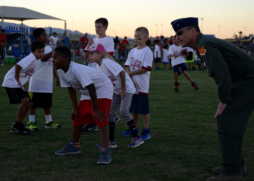 Brig. Gen. Scott Pleus, 56th Fighter Wing commander, watches as military children complete football drills during a Larry Fitzgerald ran two-day football camp at Luke Air Force Base, Arizona, Oct. 13, 2014. The camp ran by ProCamps Worldwide, specialized in football fundamentals, with campers receiving instruction from Fitzgerald and football coaches from the local area. (U.S. Air Force photo/Senior Airman Devante Williams)