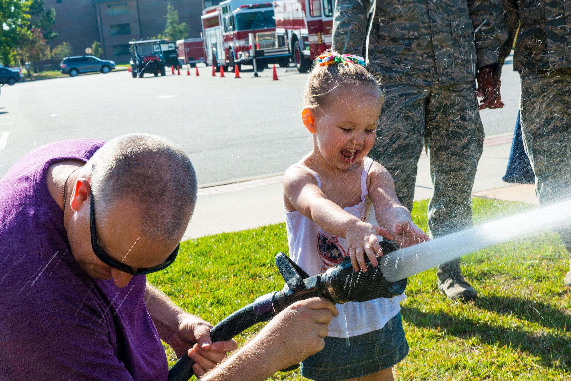 U.S. Air Force Tech. Sgt. Erik Burger, 23d Wing Public Affairs, and daughter Isabel, play with a fire hose during the National Fire Prevention Week Open House Oct. 11, 2014, at Moody Air Force Base, Ga. The theme for this year’s National Fire Prevention Week was “Working smoke alarms save lives: Test yours every month.”(U.S. Air Force photo by Airman 1st Class Ceaira Tinsley/Released)