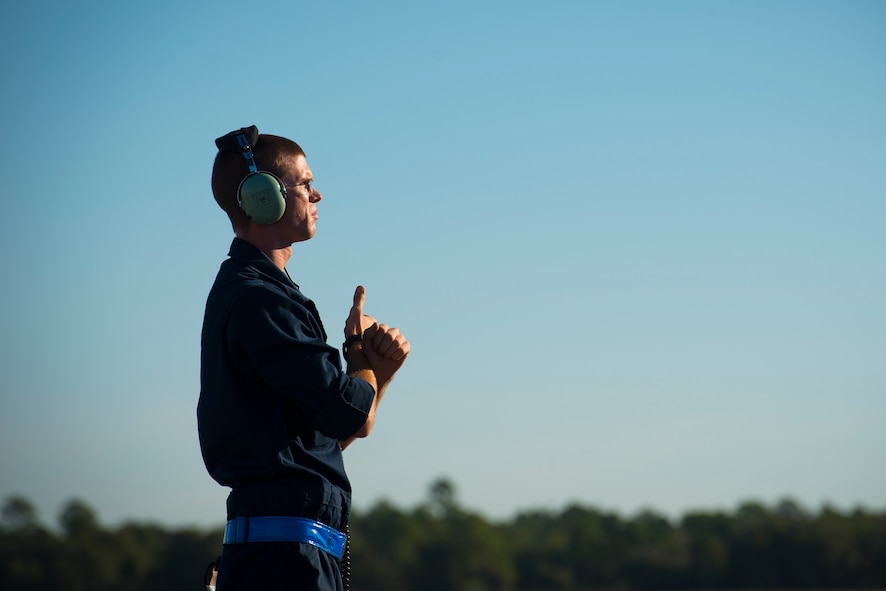 U.S. Air Force Airman 1st Class John Johnson, 74th Aircraft Maintenance Unit crew chief, signals to a pilot Oct. 9, 2014, at Avon Park Air Force Range, Fla. Crew chiefs are responsible for pre- and post-flight checks and marshalling aircraft to the taxiway. (U.S. Air Force Photo by Airman 1st Class Ryan Callaghan/Released)