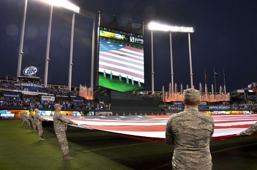 Airmen from the 442d Fighter Wing stretch the giant flag on the field of Royals stadium October 14, 2014 with their counterparts from the Army and active duty Air Force out of Whiteman Air Force Base. More than 100 volunteers from Whiteman AFB participated in the flag detail that accompanied the national anthem and an aircraft flyover that open the third game of the American League Central Series. (Air Force photo by Tech. Sgt. Emily F. Alley)