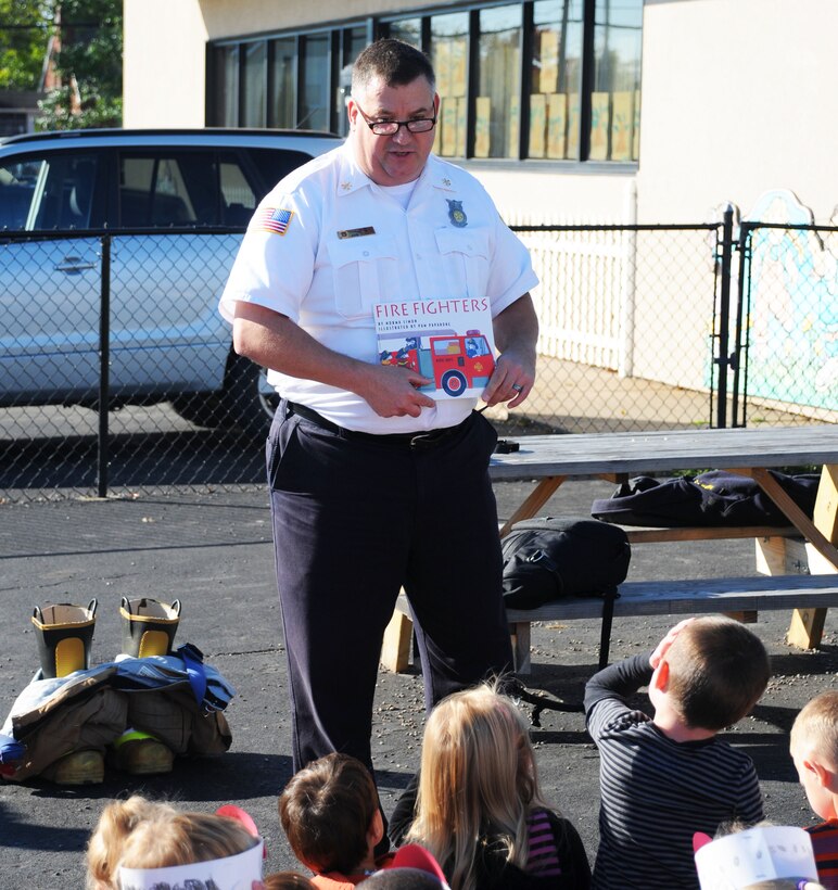 John P. Schultz, Asst. Chief, Fire Prevention, 914th Mission Support Group, reads to children at a local school, October 9 2014. Shultz was teaching the students basic fire safety for Fire Prevention Week which ran from Oct. 5-11. (U.S. Air Force Photo by Staff Sgt. Matthew Burke)