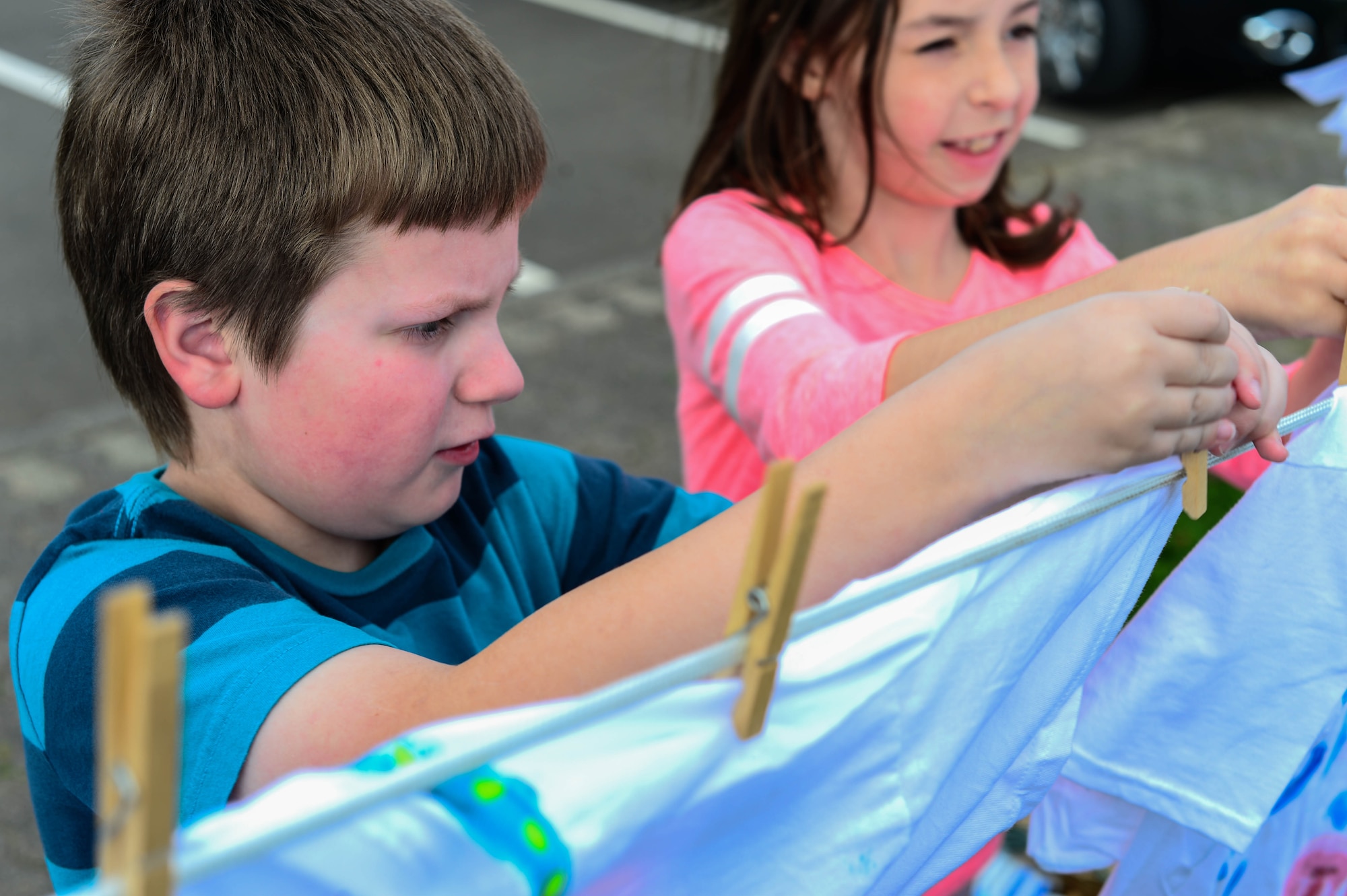 Merrick Steigerwald, son of U.S. Air Force Maj. Scott Steigerwald, 52nd Aerospace Medicine Squadron Bio-environmental Flight commander, helps hang shirts on a clothes line at the school age building on Spangdahlem Air Base, Germany, Oct. 15, 2014. The Clothes Line Project is a domestic violence awareness campaign that began in Massachusetts in 1990 and has spread to be an international event. (U.S. Air Force photo by Airman 1st Class Kyle Gese/Released)