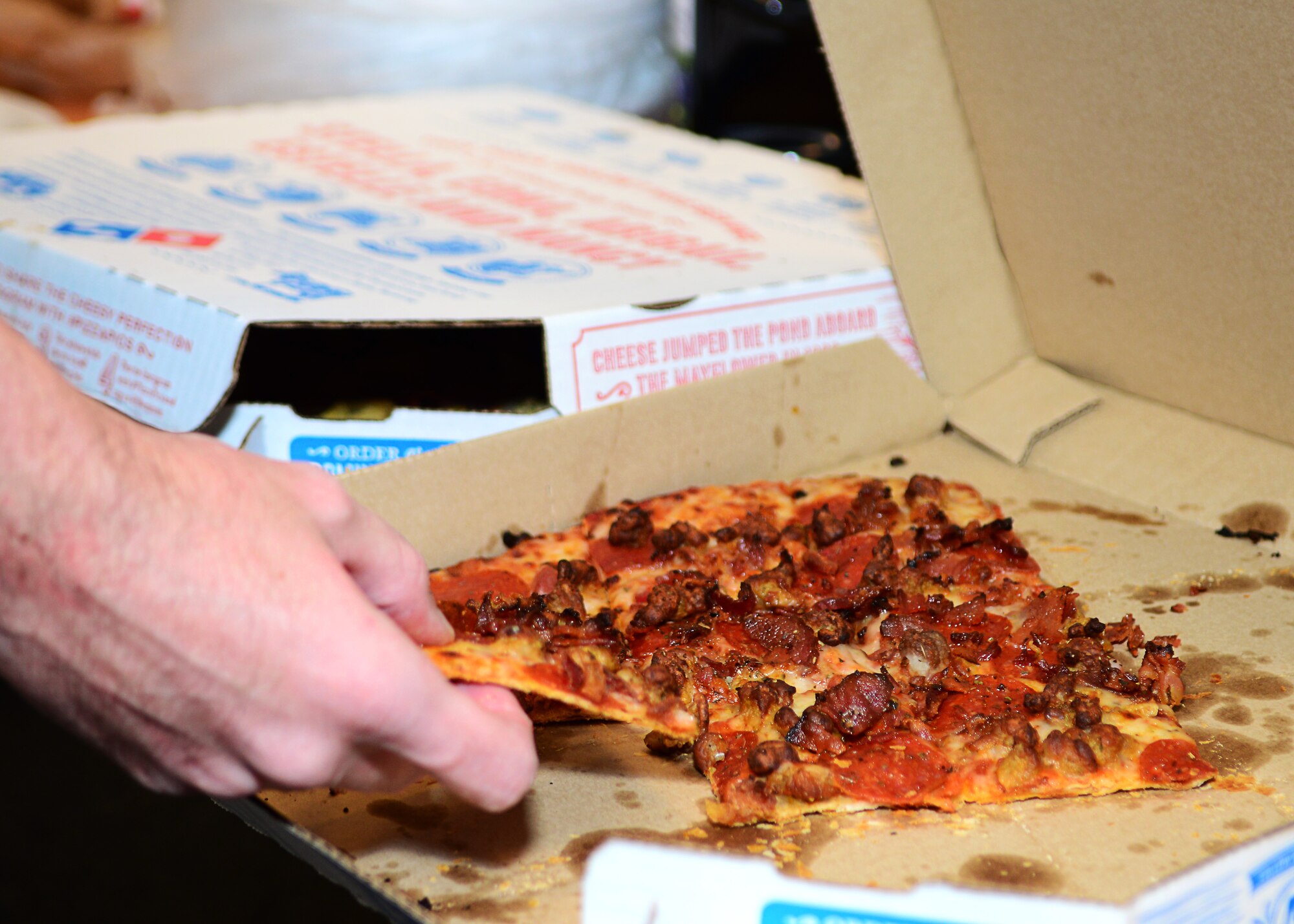 U.S. Air Force Airman 1st Class John Watson, 860th Network Operations Squadron cyber operations technician, takes a piece of pizza during a dormitory bible study at Langley Air Force Base, Va., Sept. 30, 2014. The free dinner offered at weekly studies ranges from takeout to homemade meals. (U.S. Air Force photo by Airman 1st Class Devin Scott Michaels/Released)