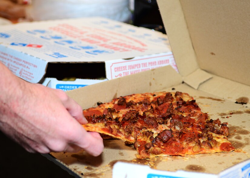 U.S. Air Force Airman 1st Class John Watson, 860th Network Operations Squadron cyber operations technician, takes a piece of pizza during a dormitory bible study at Langley Air Force Base, Va., Sept. 30, 2014. The free dinner offered at weekly studies ranges from takeout to homemade meals. (U.S. Air Force photo by Airman 1st Class Devin Scott Michaels/Released)