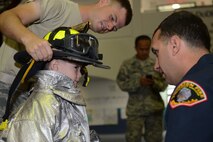 Members of the 36th Civil Engineer Squadron Fire and Emergency Services assist a student from Andersen Elementary School gear up on Andersen Air Force Base, Guam Oct. 8, 2014. 36th CES visited the elementary school part of Fire Prevention week to raise awareness. (U.S. Air Force photo by Airman 1st Class Adarius Petty/Released)