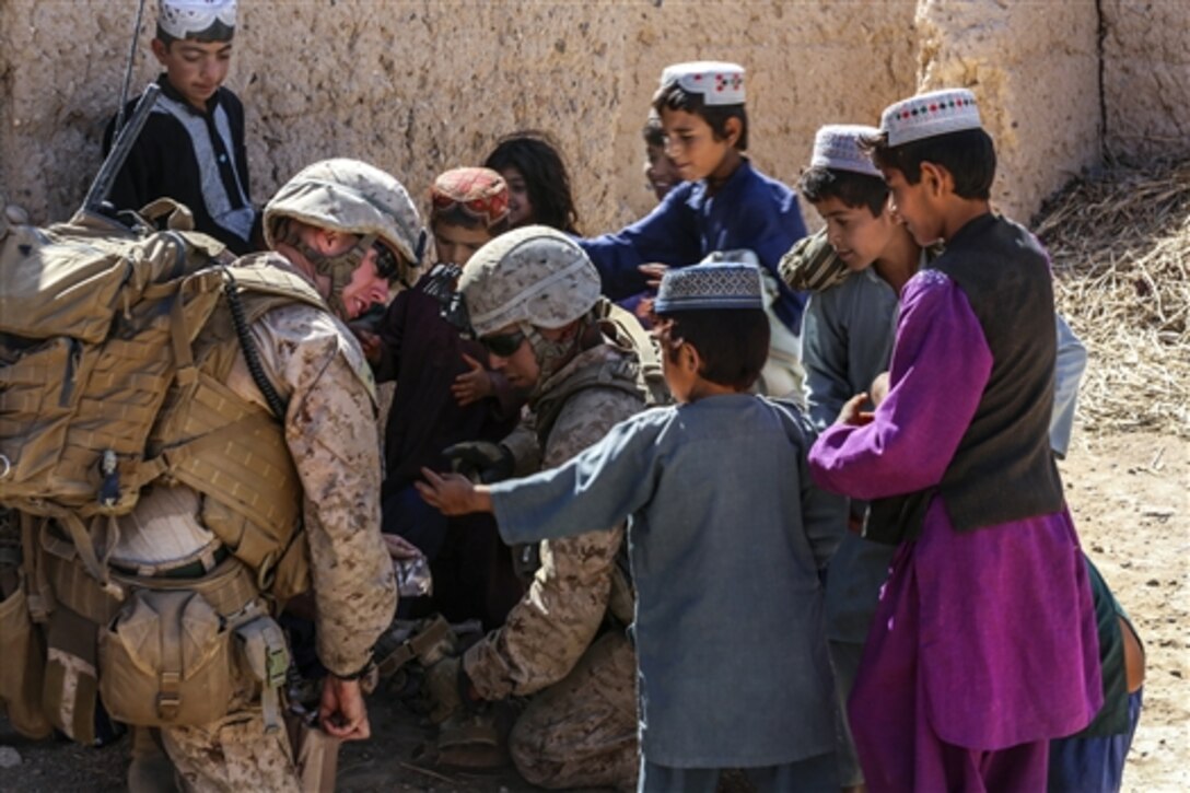U.S. Marine Corps 1st Lt. Patrick Ford, left, and Sgt. Wilfredo Rios hand out meals to local Afghan children during a security patrol in Nad Ali district in Helmand province, Afghanistan, Oct. 7, 2014. Ford is a platoon commander and Rios is a section leader assigned to Bravo Company, 1st Battalion, 2nd Marine Regiment.