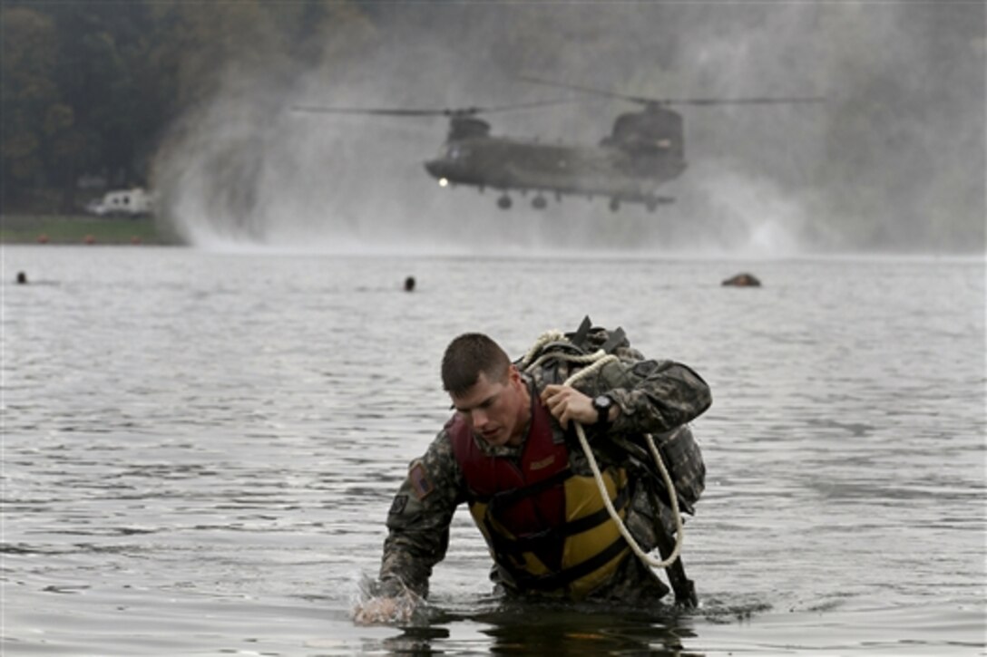Army Sgt. Max Wolfer exits the water carrying his rucksack after jumping from a CH-47 Chinook helicopter into American Lake on Joint Base Lewis-Mcchord, Wash., Oct. 9, 2014. Wolfer is a combat engineer assigned to the 571st Sapper Company, 864th Engineer Battalion.