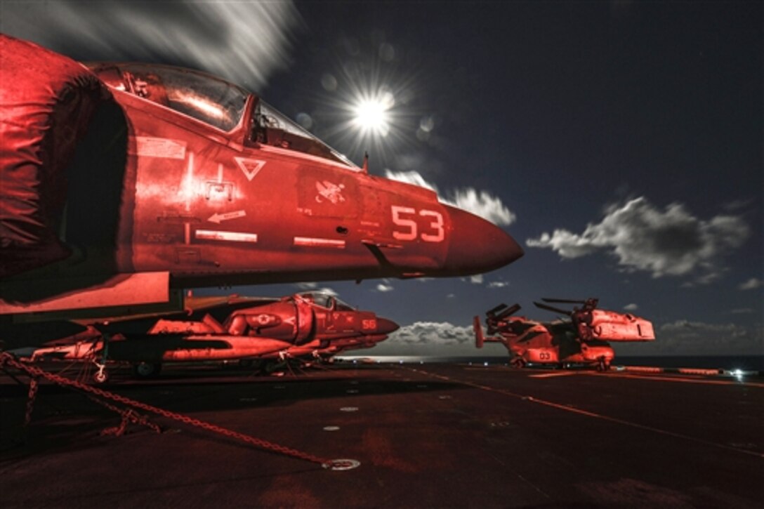 AV-8B Harriers and an MV-22 Osprey sit on the flight deck at night aboard the amphibious assault ship USS Bataan in the Mediterranean Sea, Oct. 8, 2014. The Bataan Amphibious Ready Group is on a scheduled deployment supporting maritime security operations, providing crisis response capability and theater security cooperation efforts in the U.S. 6th Fleet area of responsibility.