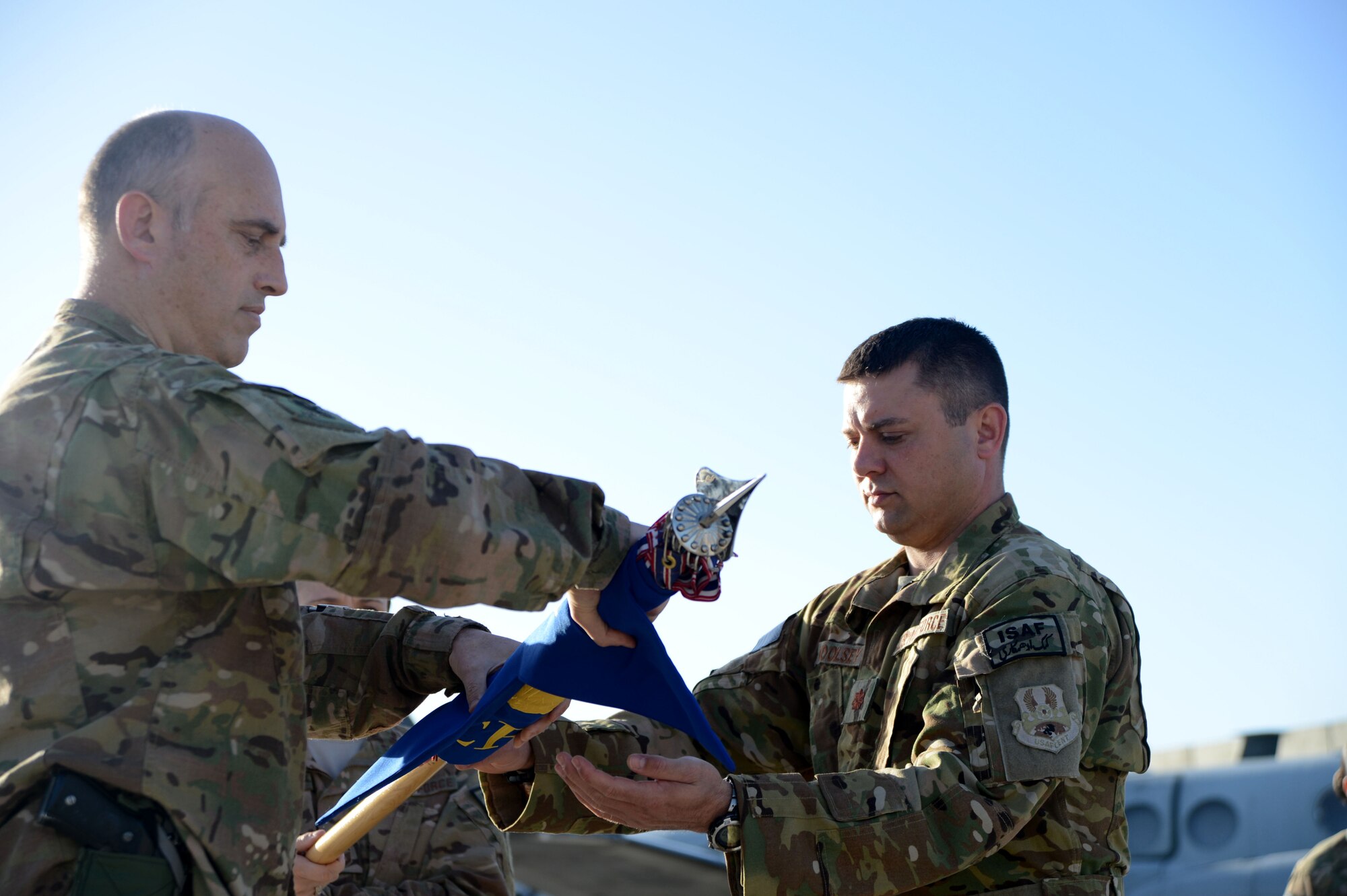 U.S. Air Force Col. Jon Wilkinson, 455th Expeditionary Operations Group commander works with Maj. Tanner Woolsey, 4th Expeditionary Reconnaissance Squadron commander, to roll the squadron’s guidon before sheathing it during the 4 ERS transition of authority ceremony at Bagram Airfield, Afghanistan Oct. 1, 2014. With the inactivation of 4 ERS, Joint Task Force Thor is now the lead for the MC-12W mission in Afghanistan. (U.S. Air Force photo by Master Sgt. Cohen A. Young/Released)