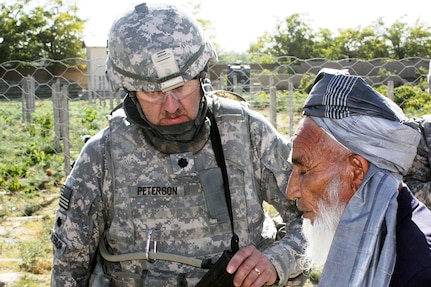 Lt. Col. Toby Peterson, a member of the Kentucky National Guard's Agri-business Development Team, listens as Hijig Mohammad Walli discusses the progress of local vineyard near Janquadm, Parwan province, Sep. 25, 2009. Peterson stands outside the section of the vineyards where trellising is being introduced as a new method for local grape production.