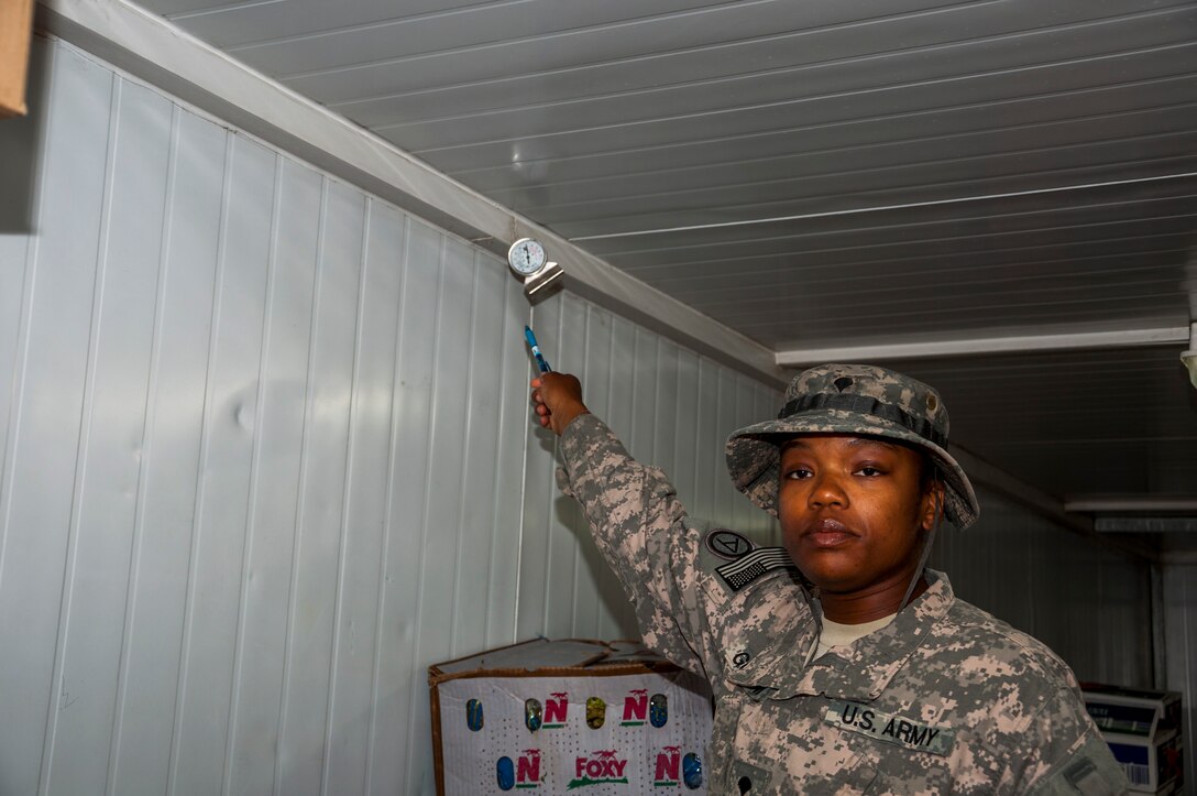 Army Spc. Juanetta Goldwire, 719th Medical Detachment Veterinary Services points at a temperature gage that she checks to determine if food is being stored at the correct temperatures in a refrigerated container outside the main dining facility at The Rock Aug. 7, 2014. As a food inspector, Goldwire’s primary mission is to reduce the risks to public health associated with diseases and other health hazards in food that is designated for more than 3,000 Airmen, Soldiers, Marines, Sailors and contractors reasons. Goldwire deployed here from the 719th MDVS, Fort Sheridan, Illinois. (U.S. Air Force photo by Senior Master Sgt. Allison Day)