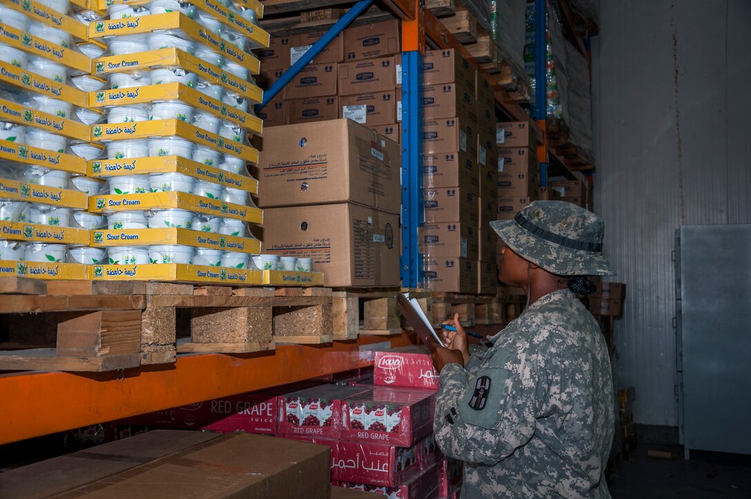 Army Spc. Juanetta Goldwire, 719th Medical Detachment Veterinary Services checks the expiration label on food stored at the rations warehouse at The Rock Aug. 7, 2014. As a food inspector, Goldwire’s primary mission is to reduce the risks to public health associated with diseases and other health hazards in food that is designated for more than 3,000 Airmen, Soldiers, Marines, Sailors and contractors reasons. Goldwire deployed here from the 719th MDVS, Fort Sheridan, Illinois. (U.S. Air Force photo by Senior Master Sgt. Allison Day)