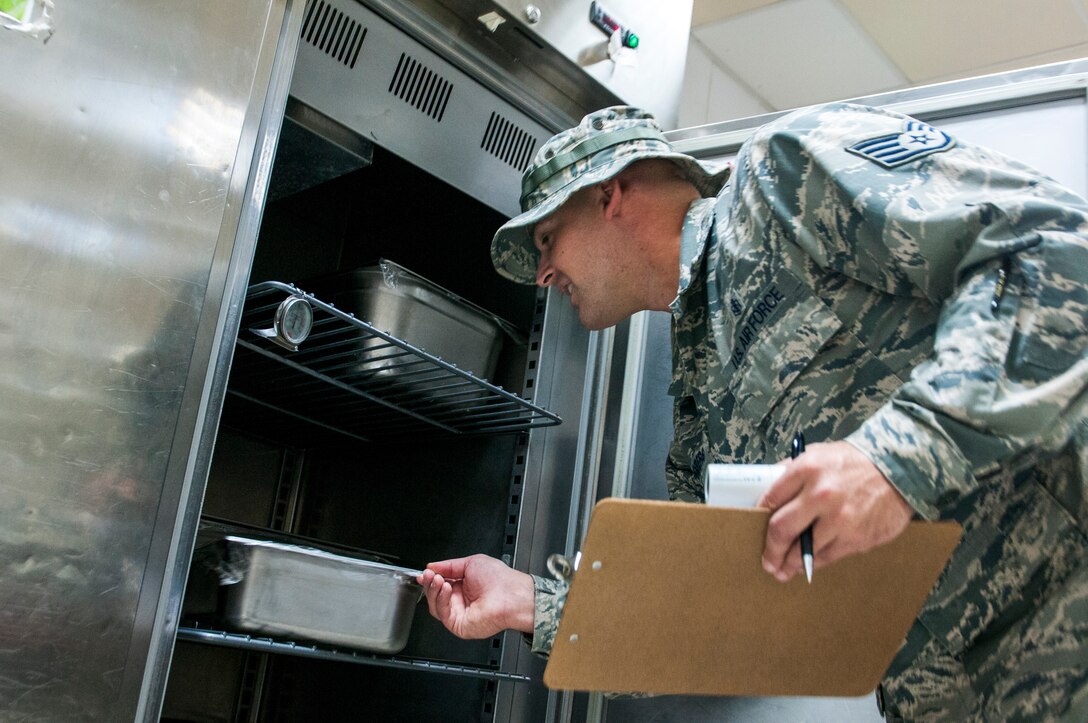 Air Force Staff Sgt. James Rodenberg, 386th Expeditionary Medical Group public health technician inspects food in a refrigerator during his inspection of the main dining facility at The Rock Sept. 23, 2014. Rodenberg conducts inspections two times each month at both dining facilities to promote good personal hygiene across the base and to ensure that facilities are operating in accordance with governing regulations. He deployed from 96th Aerospace Medicine Squadron Eglin Air Force Base, Fla., in support of Operation Enduring Freedom and is a native of Crestview, Fla. (U.S. Air Force photo by Senior Master Sgt. Allison Day)