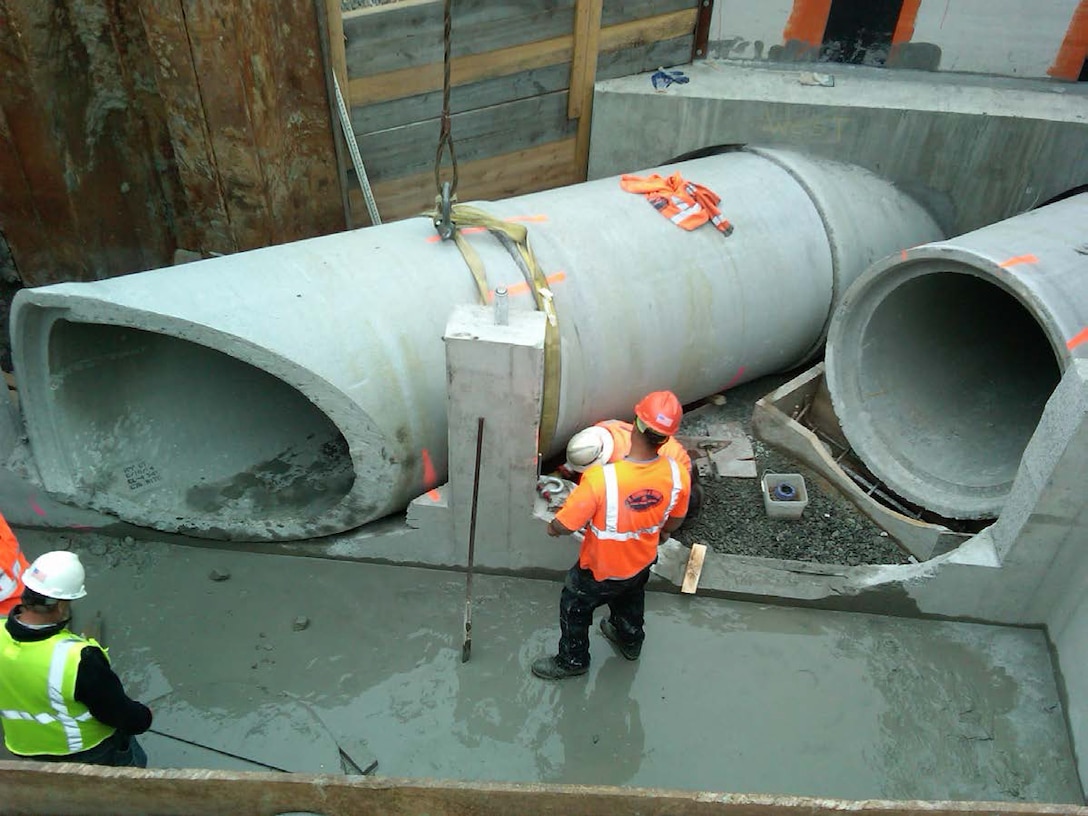 The bottom section of the permanent precast concrete junction box in place for the Muddy River Flood Risk Management Project, Boston, Mass. The second section of 54-inch pipe is being dry fit into place and has been cut to fit into the junction box opening where concrete will be placed to seal the pipe and the junction box opening.