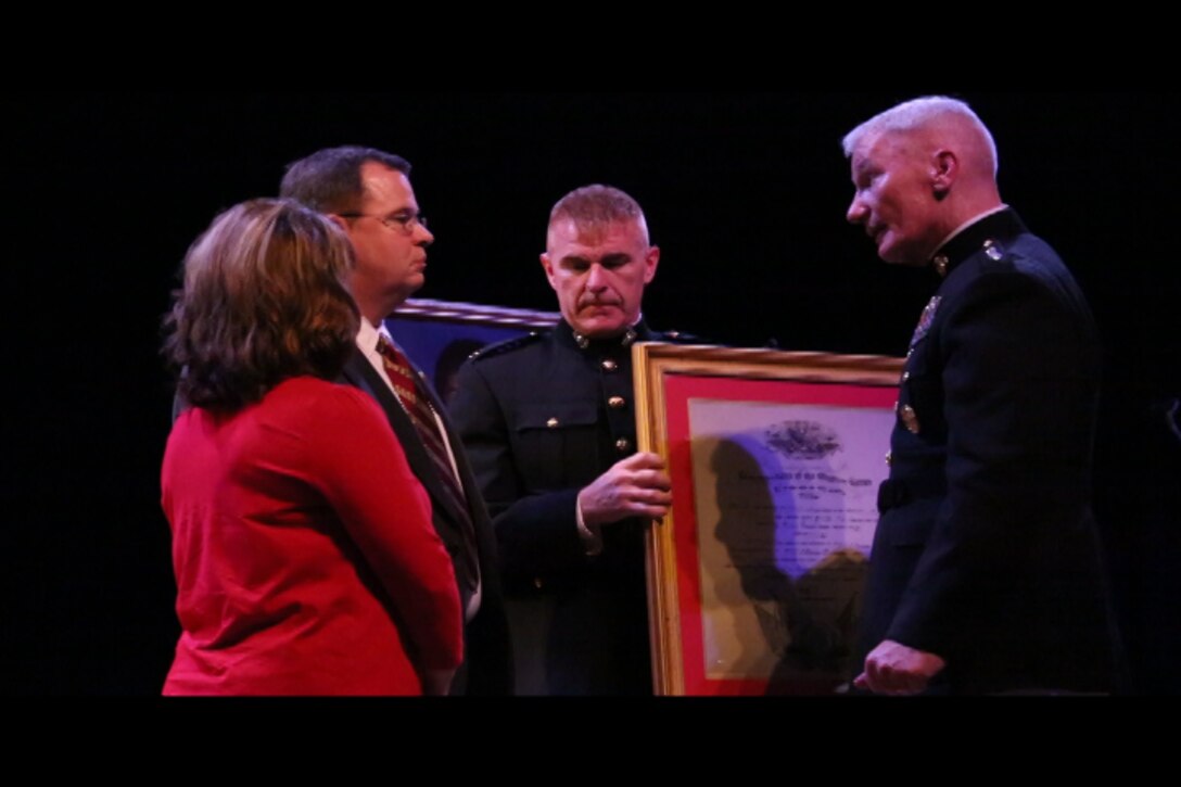 Lt. Gen. John Toolan, Marine Corps Forces, Pacific commander, presents a certificate to Rick and Monique Sprinkle during an honorary Marine ceremony in Jonesville, Virginia on Oct. 15, 2014. Rick and Monique's son, Jacob, received the title "honorary Marine" posthumously during the ceremony.