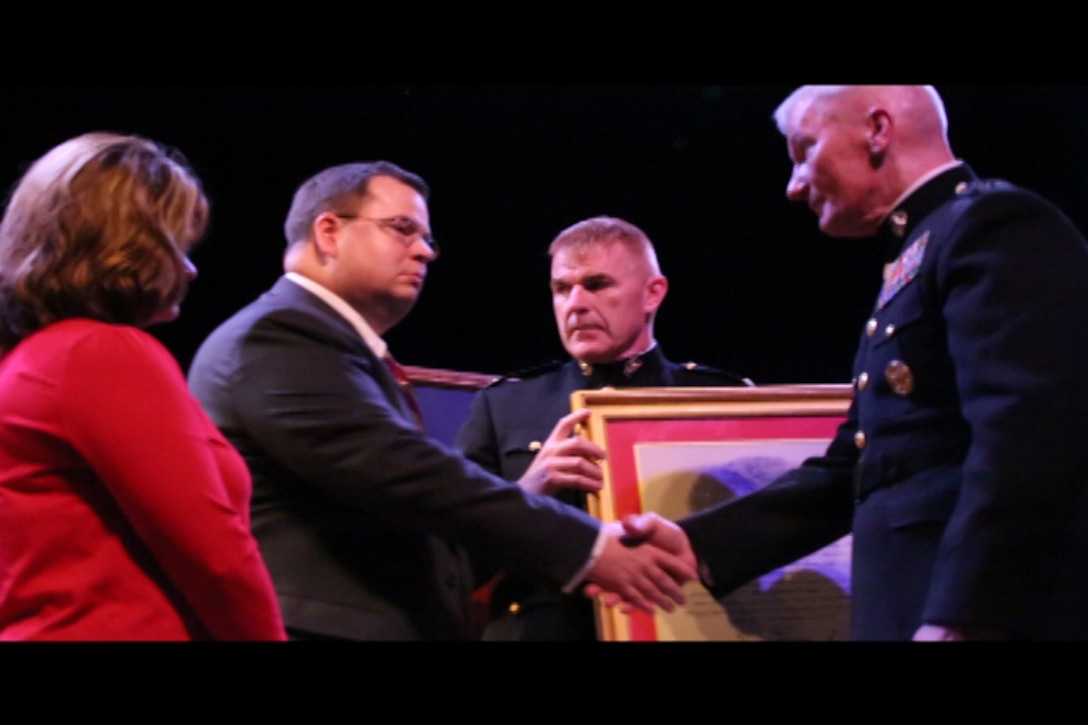 Lt. Gen. John Toolan, Marine Corps Forces, Pacific commander, presents a certificate to Rick and Monique Sprinkle during an honorary Marine ceremony in Jonesville, Virginia on Oct. 15, 2014. Rick and Monique's son, Jacob, received the title "honorary Marine" posthumously during the ceremony.