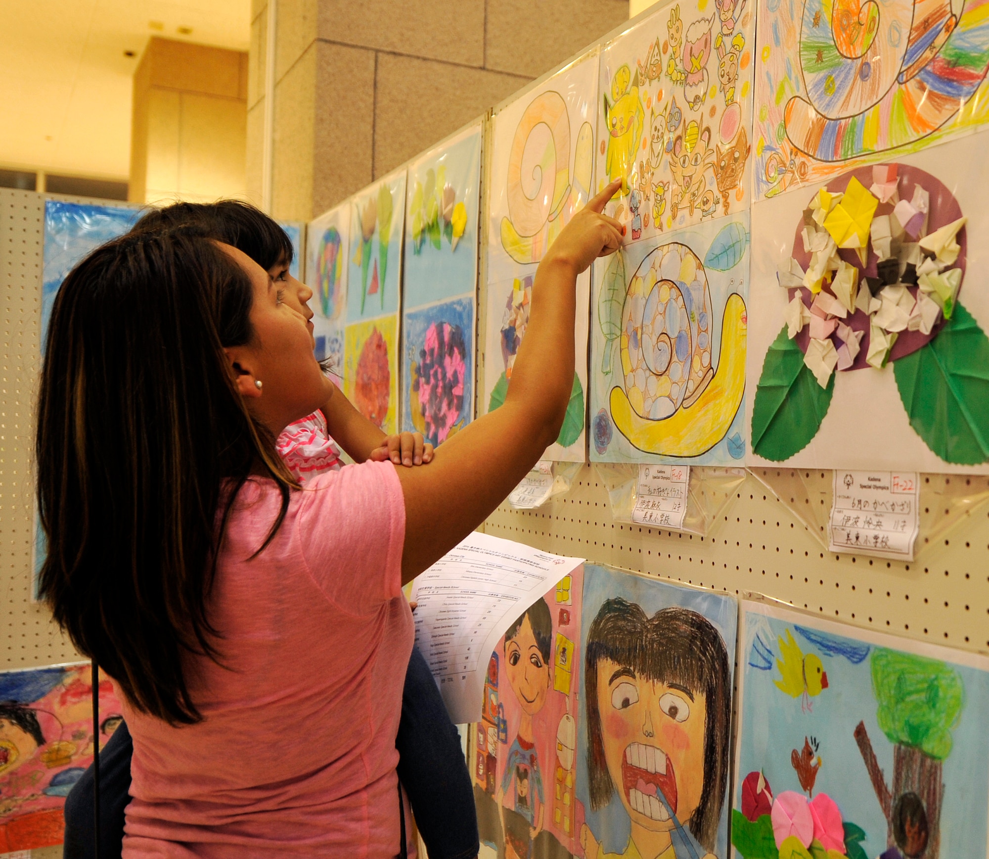 A guest points at "Pikachu" from Pokémon for her daughter during the Kadena Special Olympics art exhibit at Main City Shopping Mall San-A in Uruma City, Oct. 16, 2014. The KSO Art Exhibit has been held at Main City Shopping Mall San-A in Uruma City since 2006. The event was hosted by the Kadena Special Olympics committee to raise awareness and showcase the talents of athletes preparing for the upcoming 15th Annual KSO scheduled for Nov. 8. (U.S. Air Force photo by Naoto Anazawa/Released)