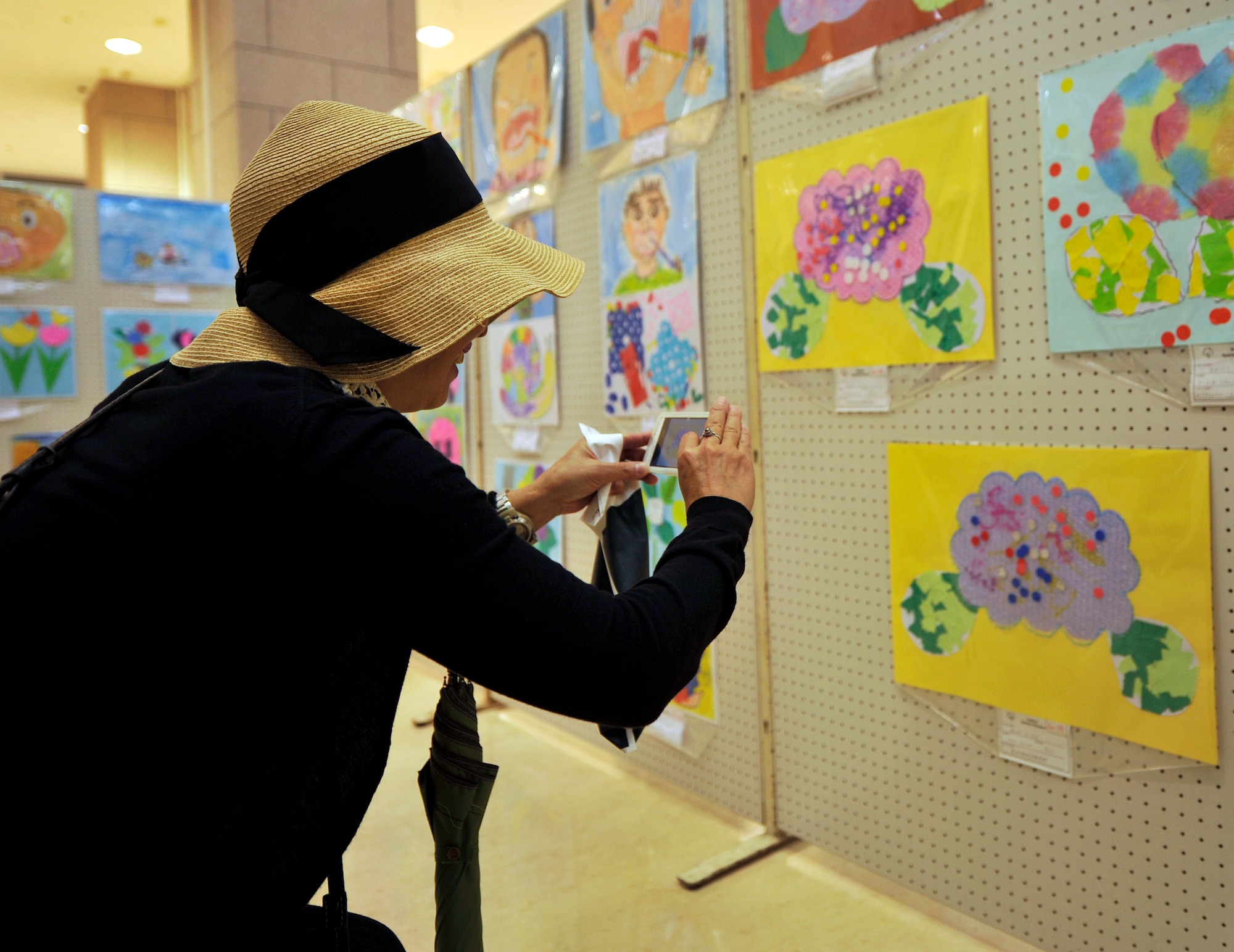 A guest takes a picture of the art during Kadena Special Olympics art exhibit at Main City Shopping Mall San-A in Uruma City, Oct. 16, 2014. The KSO Art Exhibit has been held at Main City Shopping Mall San-A in Uruma City since 2006. The event was hosted by the Kadena Special Olympics committee to raise awareness and showcase the talents of athletes preparing for the upcoming 15th Annual KSO scheduled for Nov. 8. (U.S. Air Force photo by Naoto Anazawa/Released)
