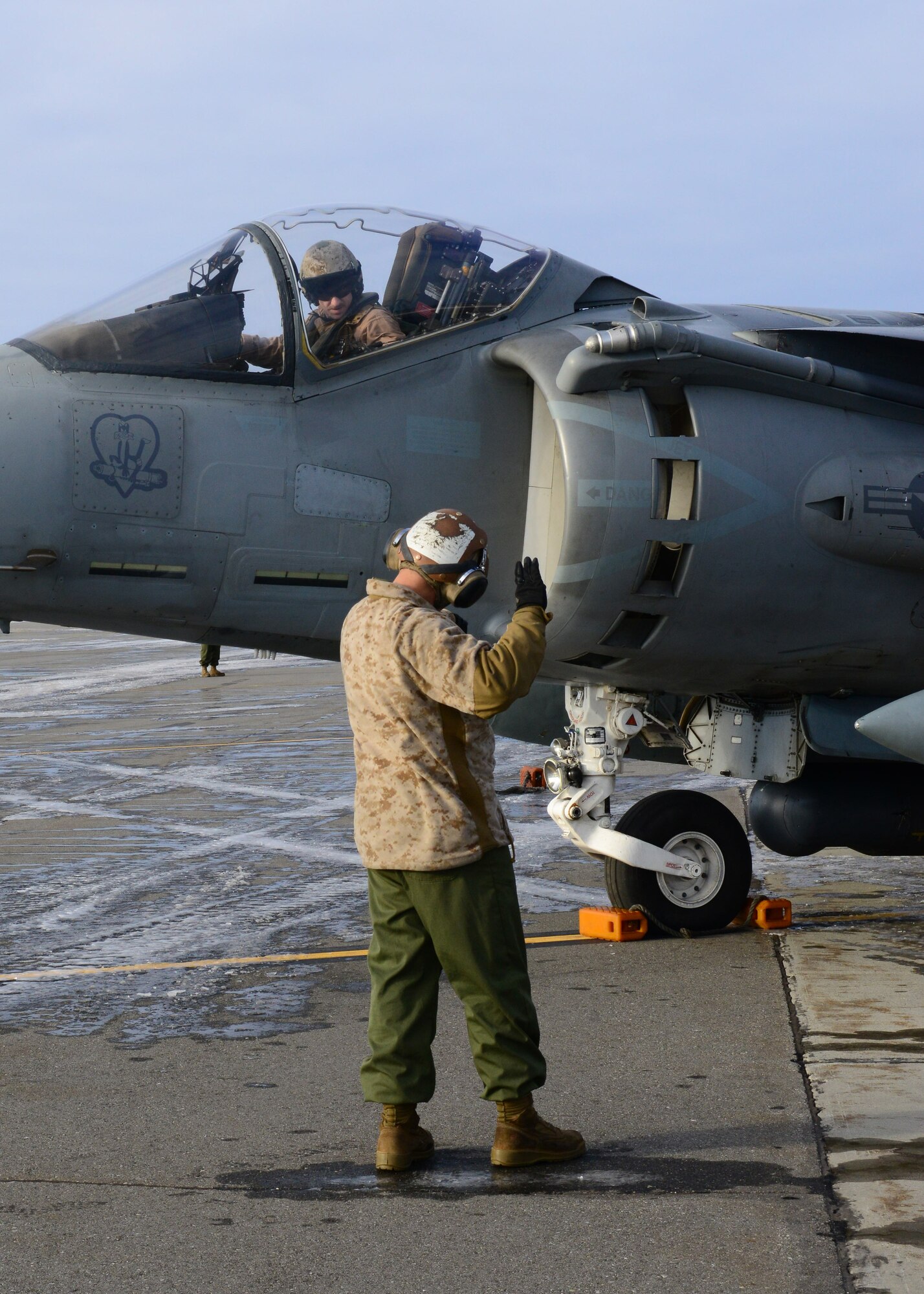U.S. Marine Corps Cpl. Cody Davenport, a Marine Attack Squadron 311 ground support specialist, signals to Capt. Benjamin Boera, a VMA-311 Harrier ground attack aircraft pilot, both assigned to Marine Corps Air Station Yuma, Ariz., Oct. 8, 2014, during RED FLAG-Alaska 15-1 at Eielson Air Force Base, Alaska. RF-A is a series of Pacific Air Forces commander-directed field training exercises for U.S. and partner nation forces, providing combined offensive counter-air, interdiction, close air support and large force employment training in a simulated combat environment. (U.S. Air Force photo by Senior Airman Ashley Nicole Taylor/Released)