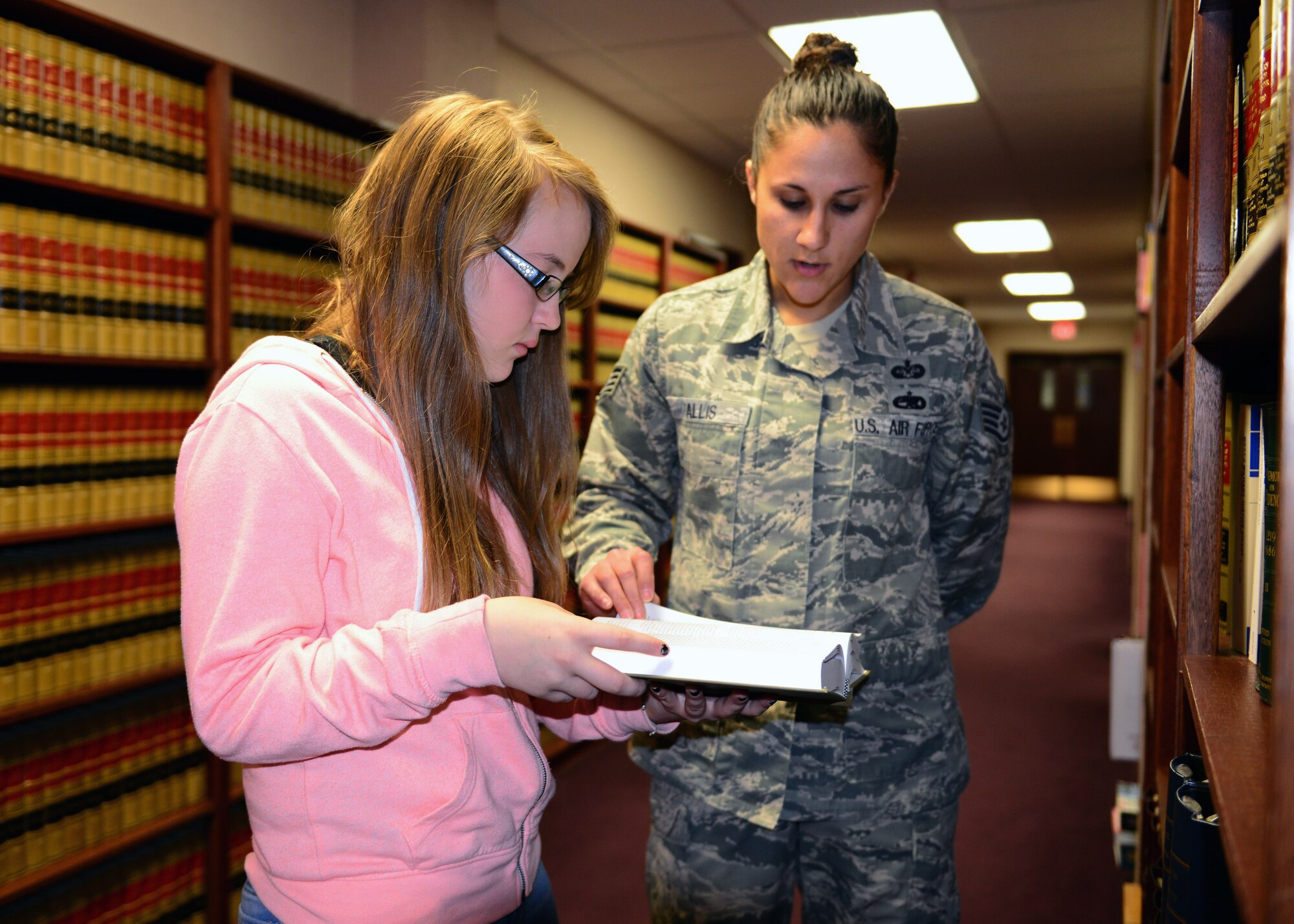 Lyndcie Carter, a 9th grader at Ben Eielson High School, looks up case law during a job shadow with Staff Sgt. Stephani Fallis, the 354th Fighter Wing legal office NCO in charge of military justice, Oct. 8, 2014, Eielson Air Force Base, Alaska. Airmen throughout base allowed students to spend eight hours with them to show the students a typical day on the job. (U.S. Air Force photo by Senior Airman Ashley Nicole Taylor/Released)