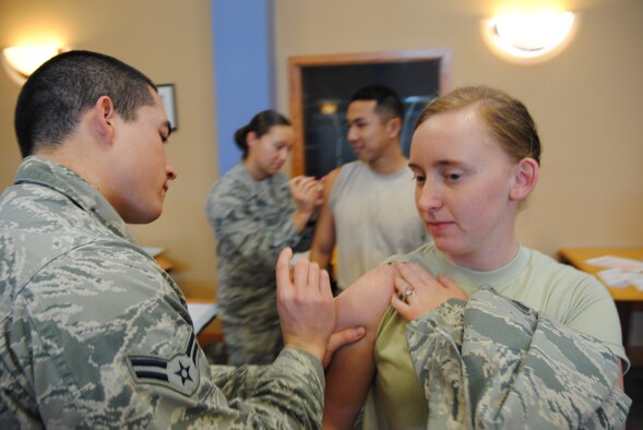 Senior Airman Bailey Holt and Airman 1st Class Ken Cummings from the 319th Medical Operation Squadron inject Airman 1st Class Bonnie Grantham and Senior Airman Xavier Navarro, with flu vaccines Oct. 10, 2014, at the Community Activities Center on Grand Forks Air Force Base, N.D. Active-duty service members are required to get vaccinations against influenza annually, unless prohibited by factors such certain allergies. (U.S. Air Force photo/Staff Sgt. Luis Loza Gutierrez) 