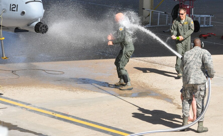 Lt. Col. Mark Ernewein gets the traditional soak in water and champaign following his final flight and landing at Whiteman AFB on October 16, 2014. His daughter and a Whiteman firefighter carried the hose. Ernewein’s flight concluded nearly 30 years as an A-10 pilot and 12 combat deployments. (Air Force photo by Tech. Sgt. Emily F. Alley)