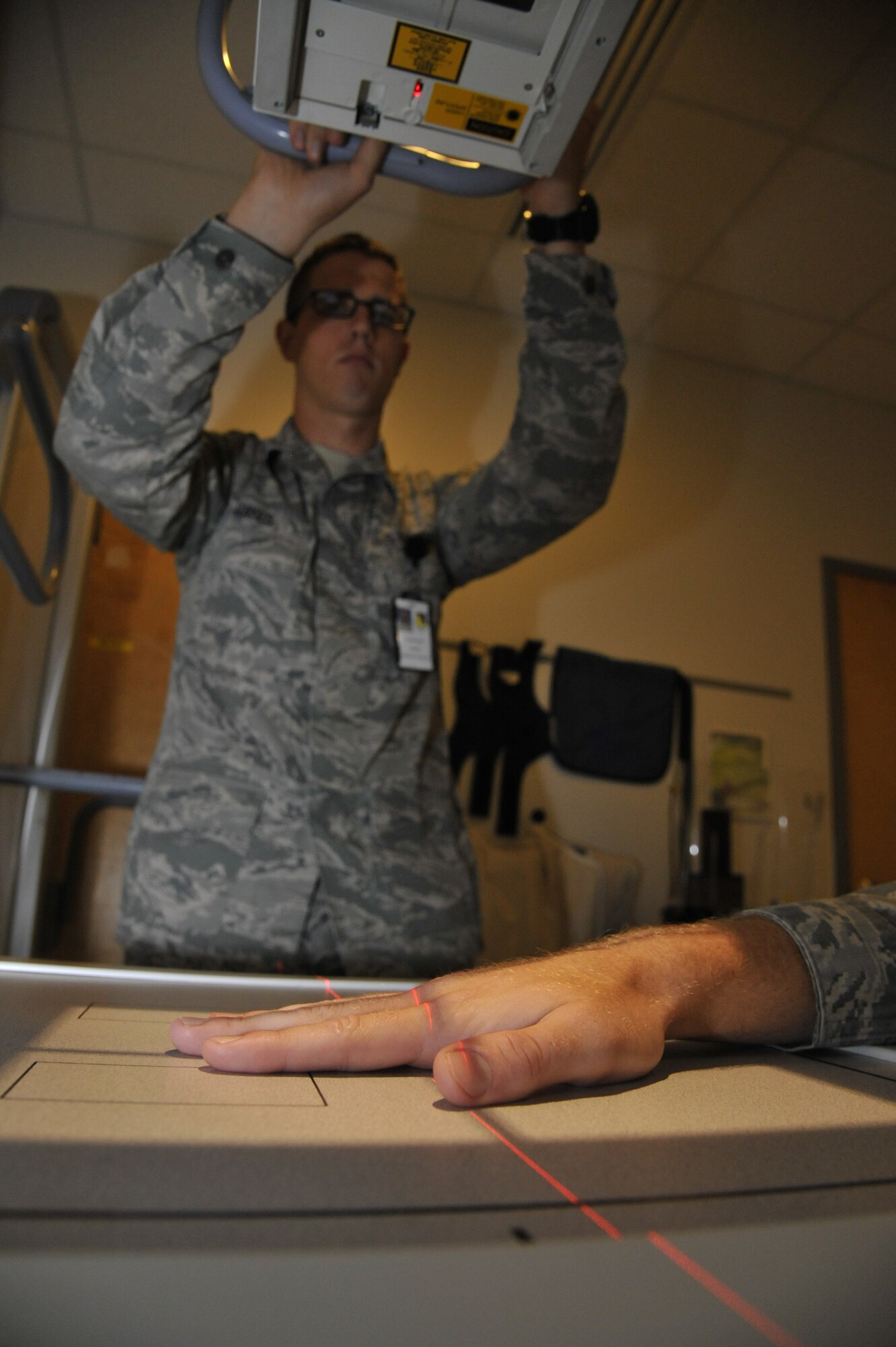 U.S. Air Force Senior Airman Steven Hayes, 509th Medical Support Squadron radiologist, positions the x-ray equipment to perform an exam at Whiteman Air Force Base, Mo., Sept. 23, 2014. This procedure is done to provide imaging of potential fracture. (U.S. Air Force photo by Airman 1st Class Keenan Berry/Released)