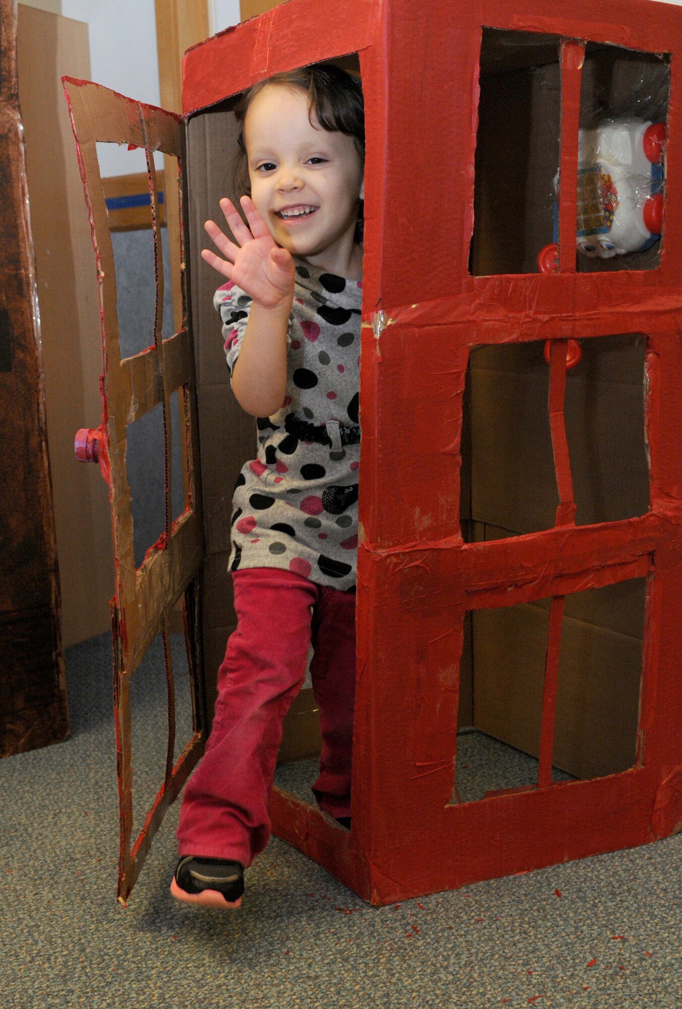 Emily Martin, 3, daughter of U.S. Air Force Tech. Sgt. Rebeca Martin, 352nd Special Operations Support Squadron aircrew flight equipment NCO in charge, and U.S. Air Force Tech. Sgt. Talon Martin, 7th Special Operations Squadron loadmaster, exits a cardboard English phone booth Oct. 10, 2014, at the Child Development Center on RAF Mildenhall, England. The phone booth was part of a whole cardboard English village created by Airmen and their families for this year’s Global Cardboard Challenge presented by the Imagination Foundation which encourages children and their communities to build items to mind out of cardboard, recycled materials and their imagination. (U.S. Air Force photo/Senior Airman Kate Maurer/Released)