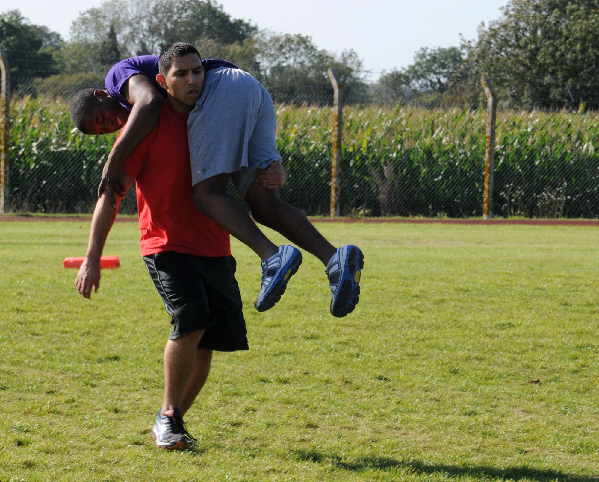 U.S. Air Force members assigned to RAF Mildenhall and RAF Lakenheath take part in a fireman carry event during a Combined Federal Campaign Fitness Challenge Oct. 9, 2014, at Heritage Park on RAF Mildenhall, England. The events were linked to military skills Airmen may need in the field, such as carrying an injured wingman to safety. In this challenge, teams were permitted to carry or drag their teammate. (U.S. Air Force photo/Gina Randall/Released)