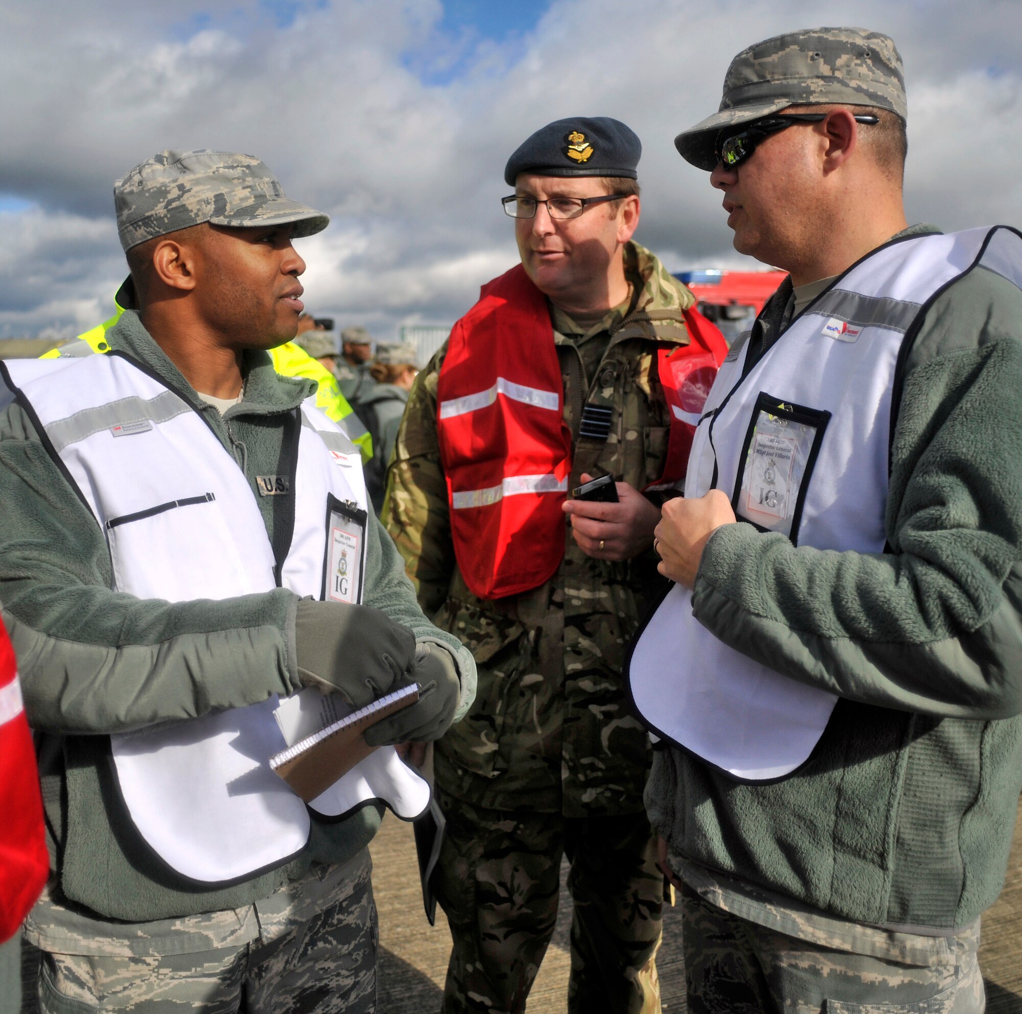 U.S. Air Force Master Sgt. Shanton Russell, left, 100th Air Refueling Wing Inspector General inspector from Chicago; Wing Commander Tim Owen, center, RAF Liaison Office Air Operations, RAF Honington exercise lead planner, and U.S. Air Force Master Sgt. Joe Villarin, 100th ARW IG superintendent from Orange Park, Fla., discuss joint operations between Suffolk Constabulary and the RAF Mildenhall Fire Department Oct. 7, 2014, during a Major Accident Response Exercise on RAF Honington, near Thetford, England. Russell, a new addition to the IG office, was part of the inspection team involved in planning the MARE. (U.S. Air Force photo/Senior Airman Christine Griffiths/Released) 