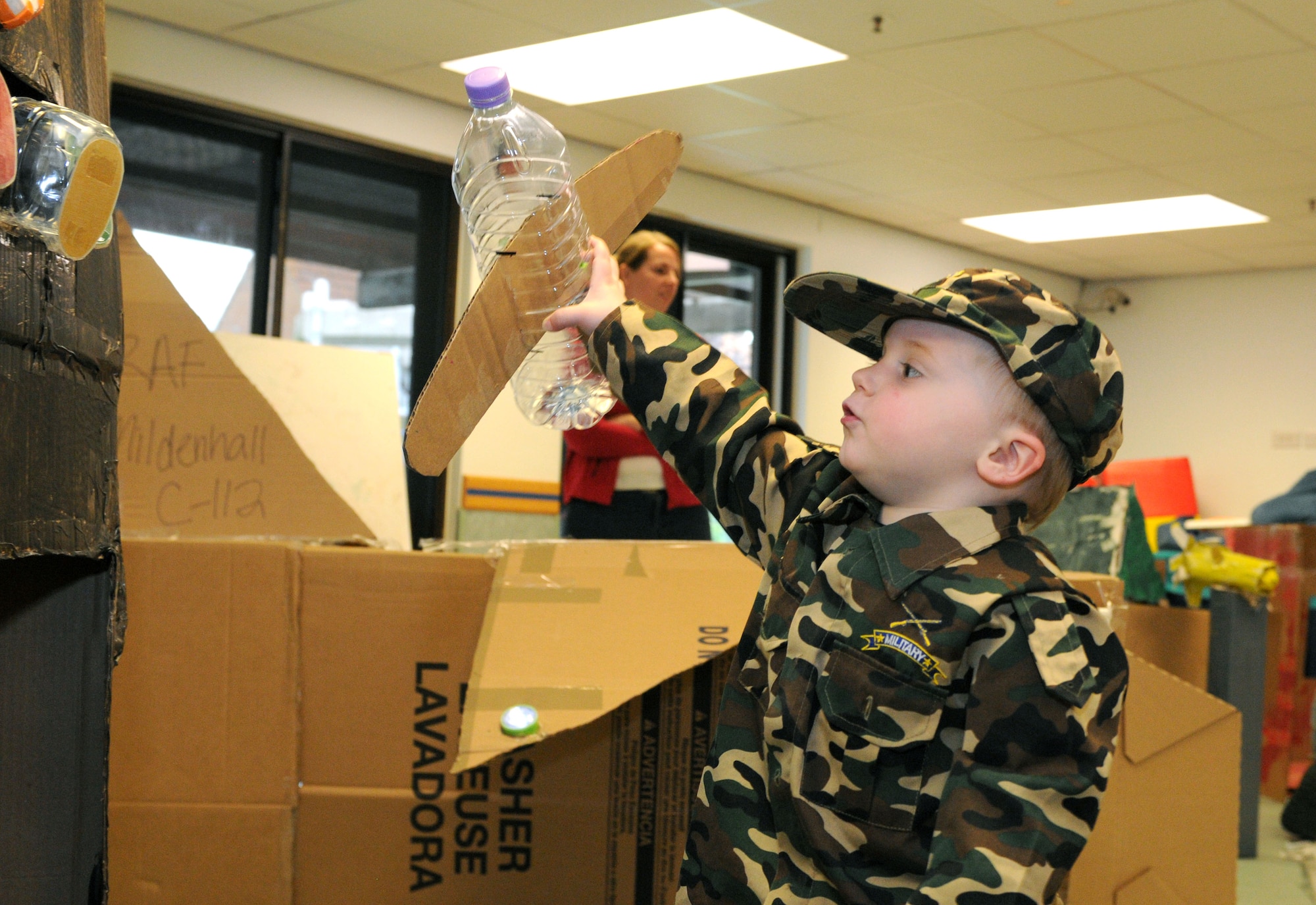 Easton May, 3, son of U.S. Air Force Tech. Sgt. Miranda May, 100th Logistics Readiness Squadron vehicle operations supervisor, plays with an airplane Oct. 10, 2014, at the Child Development Center on RAF Mildenhall, England. The airplane was part of a whole cardboard English village created by Airmen and their families for this year’s Global Cardboard Challenge presented by the Imagination Foundation which encourages children and their communities to build items to mind out of cardboard, recycled materials and their imagination. (U.S. Air Force photo/Senior Airman Kate Maurer/Released)