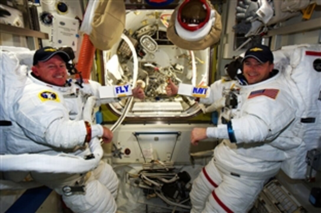 Navy Capt. Barry Wilmore, left, and Cmdr. Reid Wiseman show "Fly Navy" signs aboard the International Space Station after a spacewalk, Oct. 15, 2014. Wilmore and Wiseman are Navy pilots. Wilmore is scheduled to assume command of the International Space Station in November.