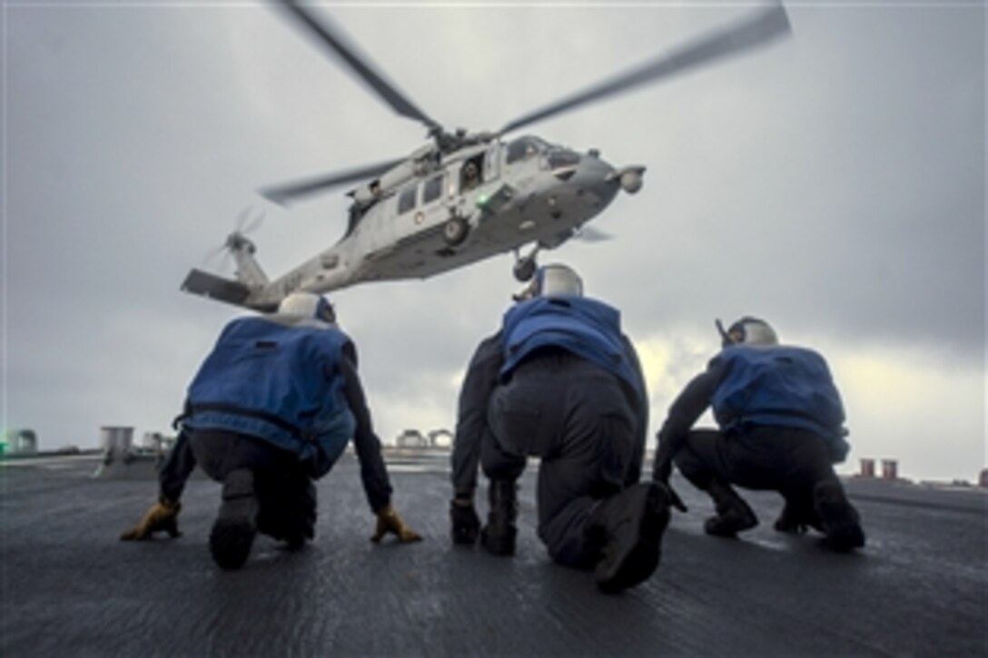 Sailors brace as an MH-60S Seahawk takes off from the flight deck of the USS Stethem, Oct. 16, 2014. The sailors are assigned to the guided-missile destroyer USS Stethem. 