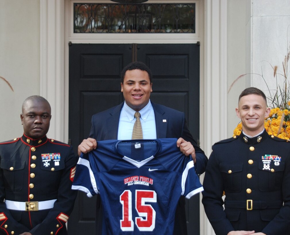 Sgt. Enock Dumarsais (left) and Capt. Zachary Smith (right) presented Grant Newsome, a senior high school football player with The Lawrenceville School, with his jersey to play in the 2015 Semper Fidelis All-American Bowl to be played in Carson, Calif., on Jan. 4, 2015. The Marines recognized Newsome as one of the top 90 student-athletes in the country in front of the entire Lawrenceville School during a ceremony, Oct 16. 