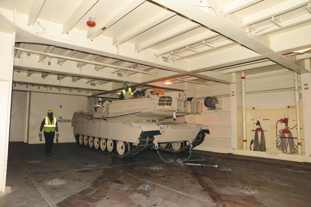 Blount Island Command, Jacksonville, Fla., employees prepare a tank to be secured on the USNS Pfc. Dewayne T. Williams, recently.