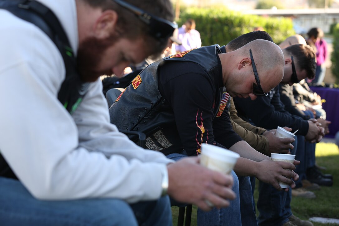 Service members bow their heads for prayer before a bike ride commemorating Domestic Violence Awareness Month at the Protestant chapel, Oct 10, 2014. The prayer was said to help prevent domestic violence and to protect the motorists on the ride they were about to take.