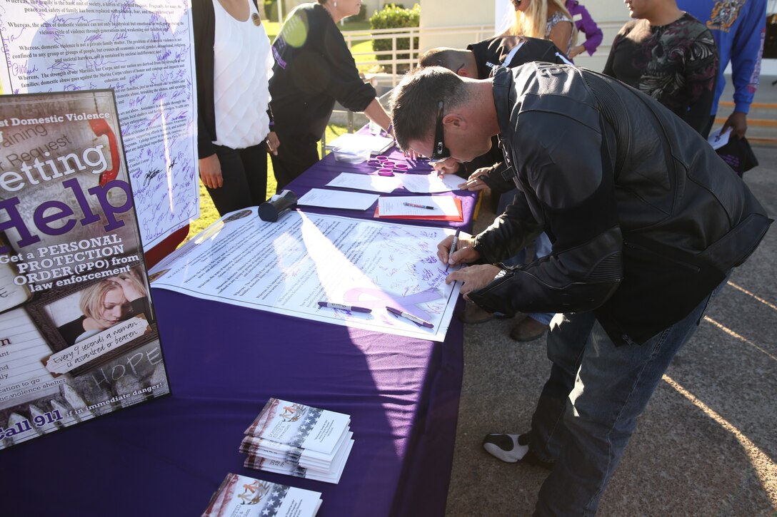 Motorists sign a pledge to help stop and prevent domestic violence before a bike ride commemorating Domestic Violence Awareness Month at the Protestant chapel, Oct. 10, 2014.