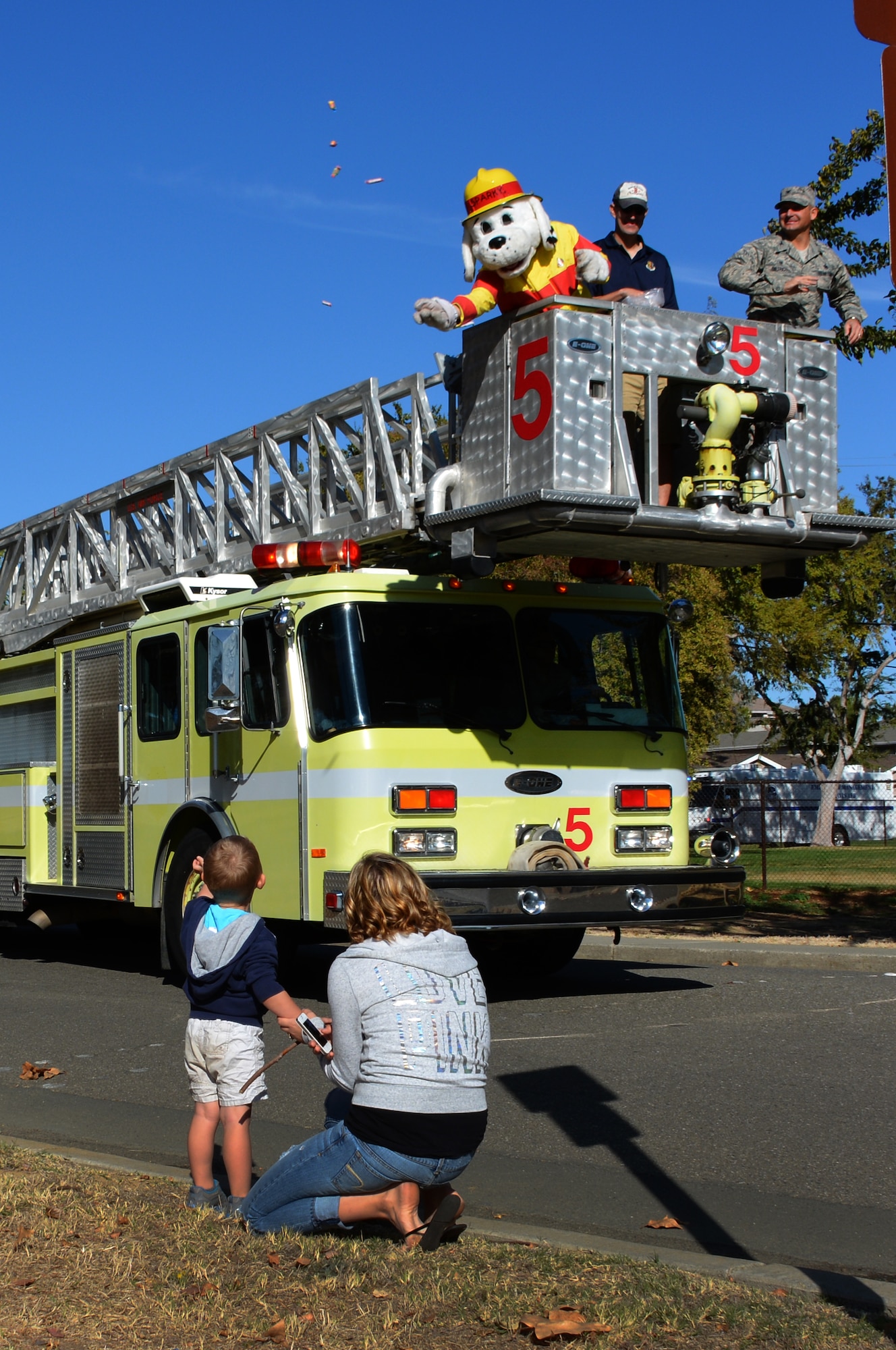 Airmen from the 60th Mission Support Group throw candy out to Travis youth Oct. 11, 2014, during the Fire Prevention Week Parade. (U.S. Air Force photo by Senior Airman Charles Rivezzo)