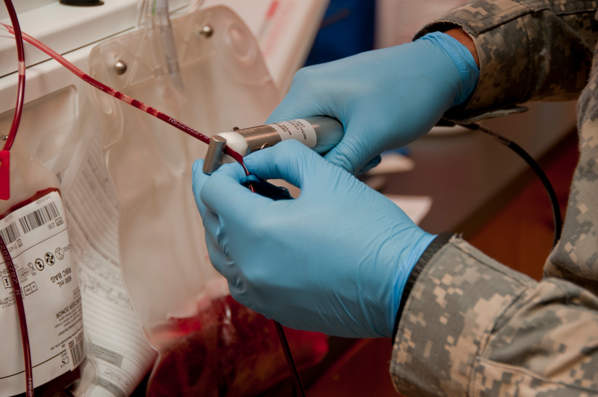 Army Sgt. Jered Whicker clamps down on medical tubing Sept. 18, 2014, in order to transport previously frozen blood to a centrifuge where it will be spun to show positive types of blood units. Whicker is one of 12 laboratory technicians who serve at the Armed Services Whole Blood Processing Laboratory West at Travis Air Force Base, California. (U.S. Air Force photo by Senior Airman Charles Rivezzo)
